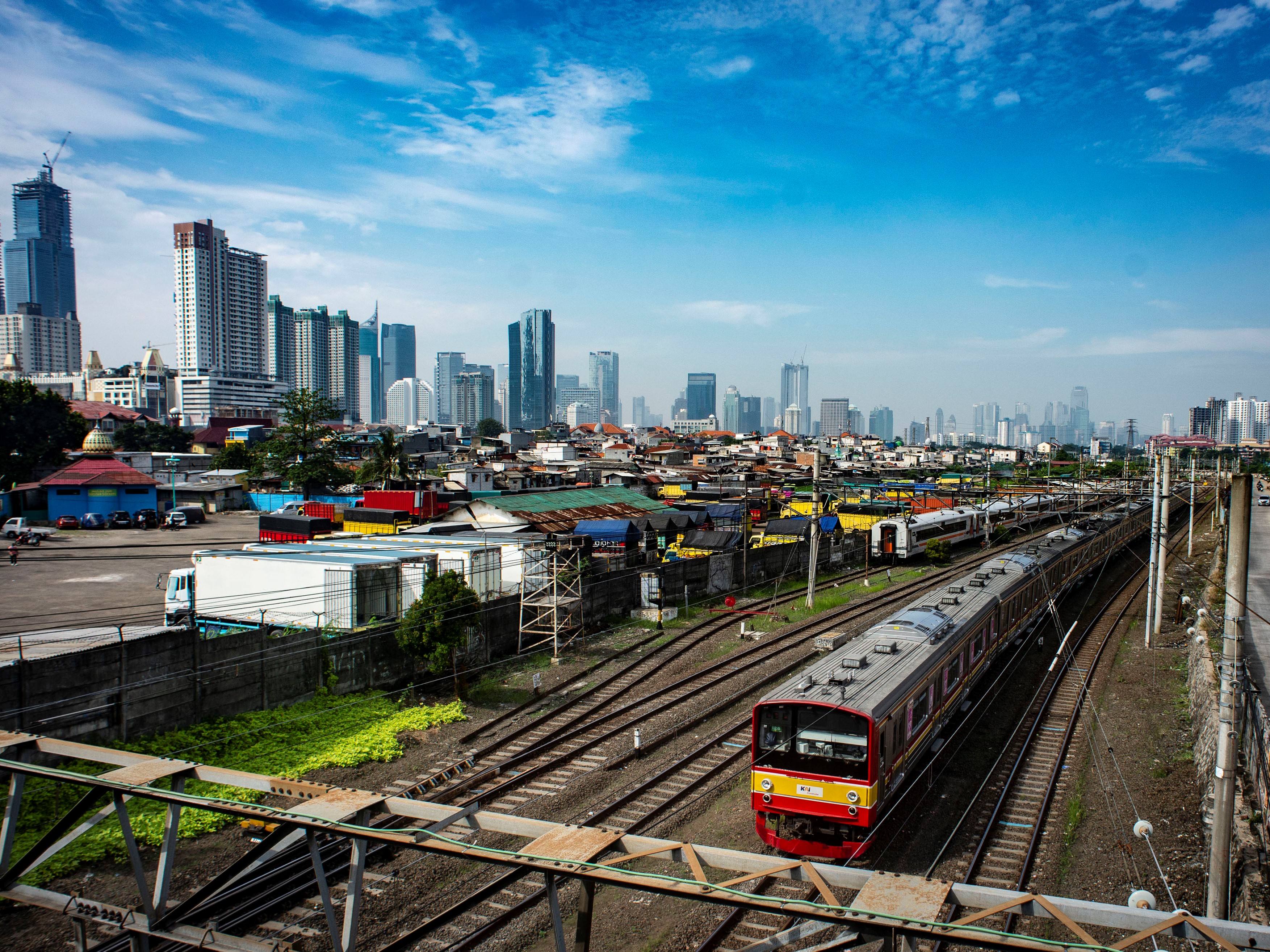 KRL melintas dengan latar belakang permukiman penduduk dan gedung bertingkat di Jakarta, Selasa (13/7).
