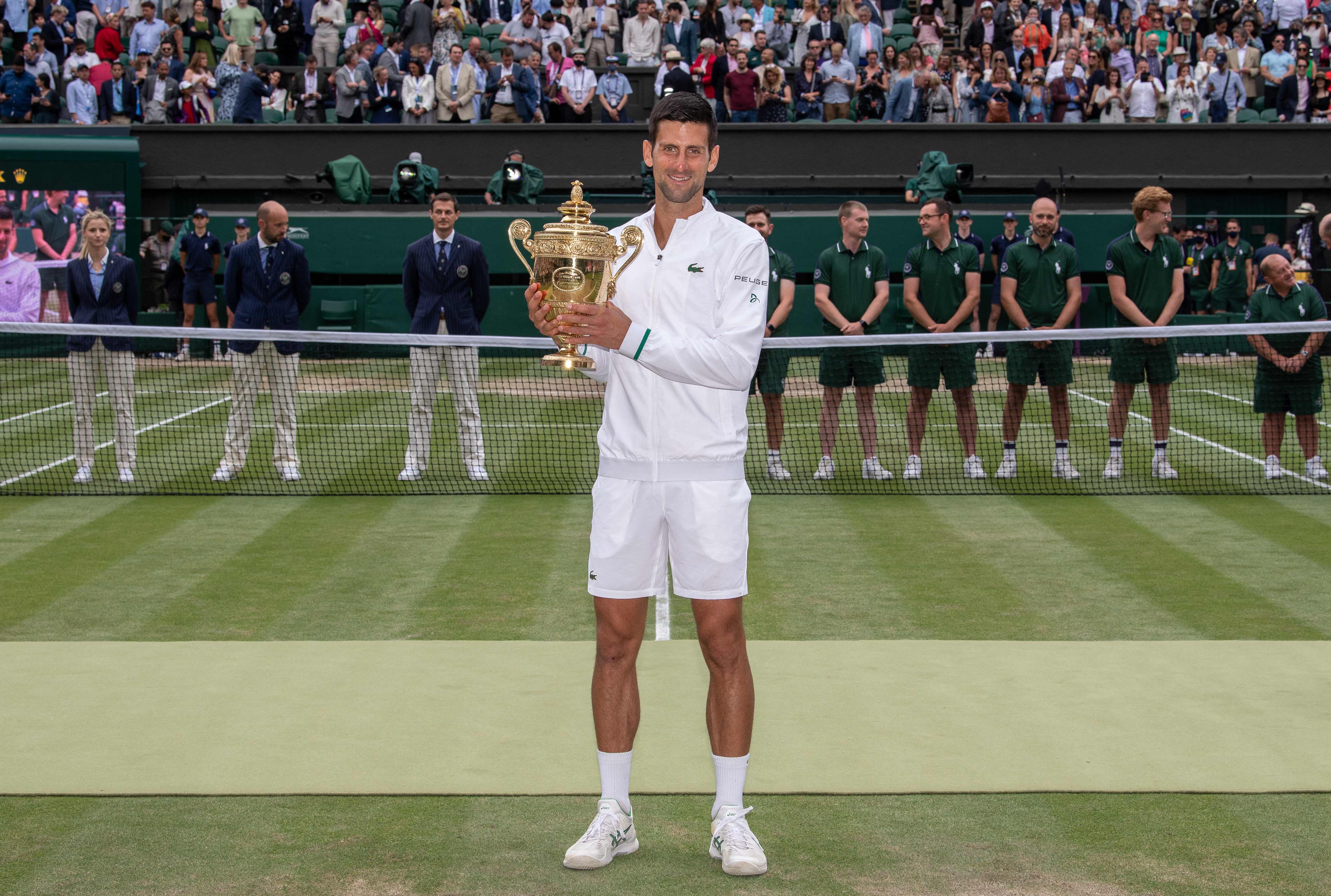 Petenis Serbia Novak Djokovic berpose dengan trofi Wimbledon.