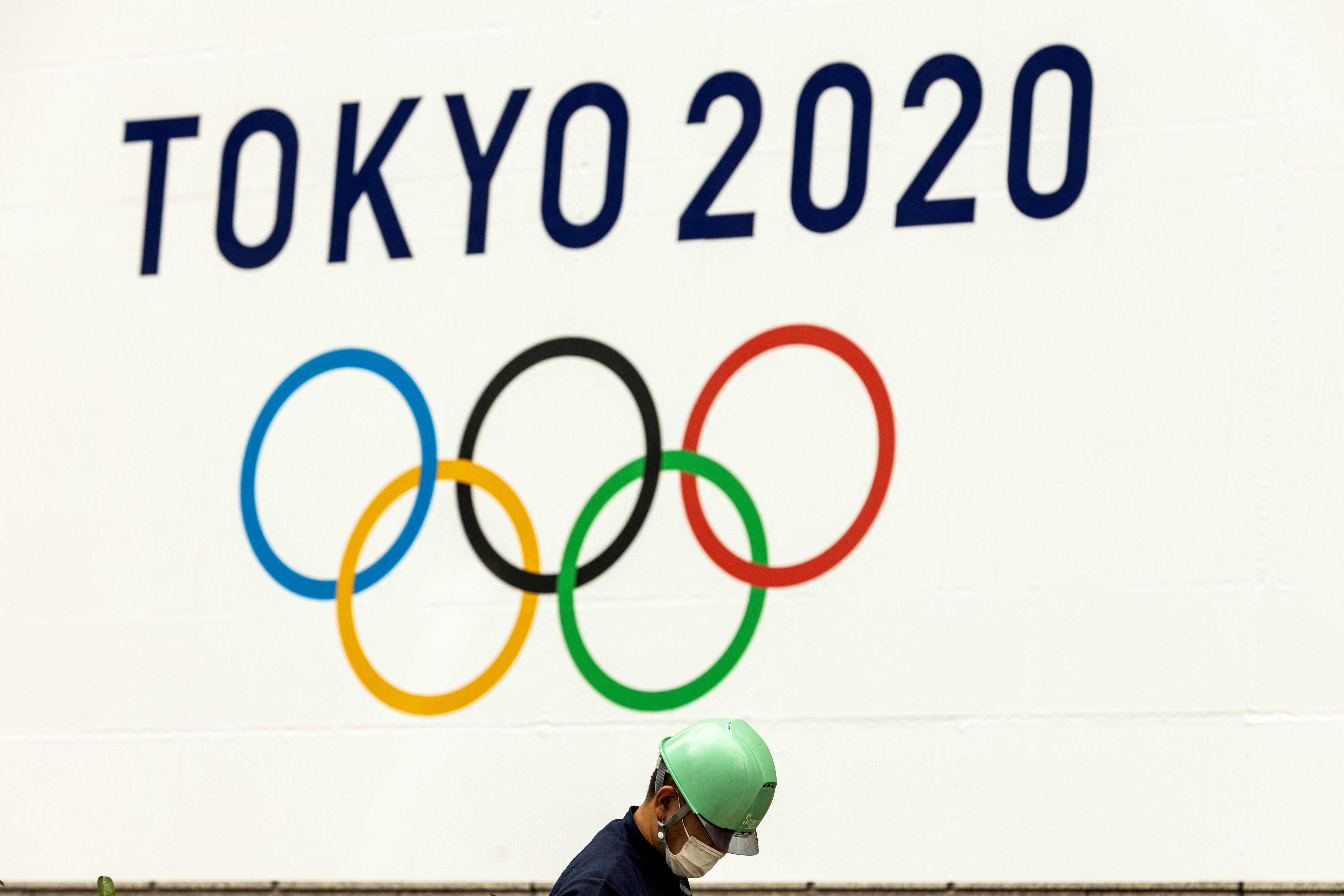 Seorang pekerja berada di bawah logo Olimpiade 2020 di Tokyo, Jepang.