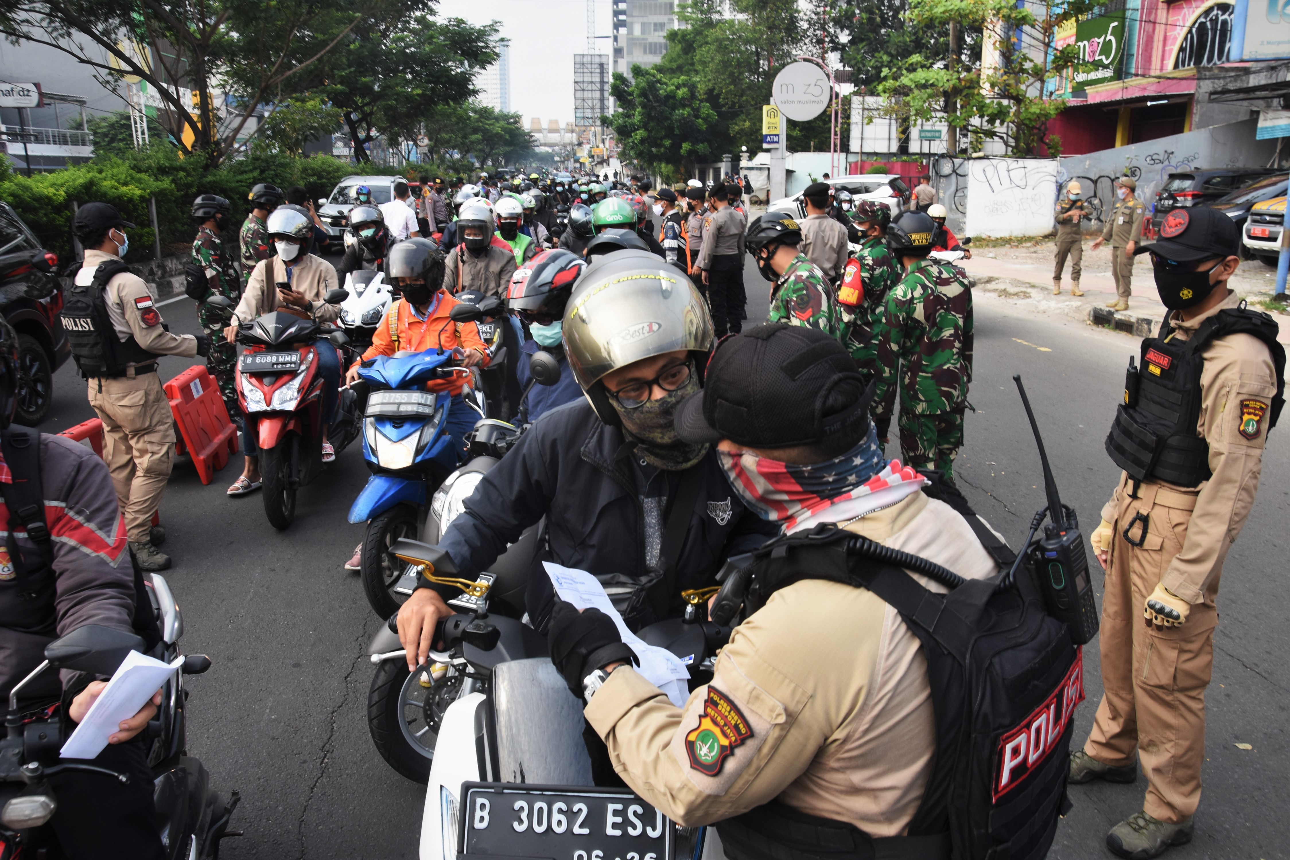 Pengendara menunjukkan STRP kepada petugas di pos penyekatan saat PPKM Darurat di perbatasan menuju Jakarta di Jalan Margonda, Depok.