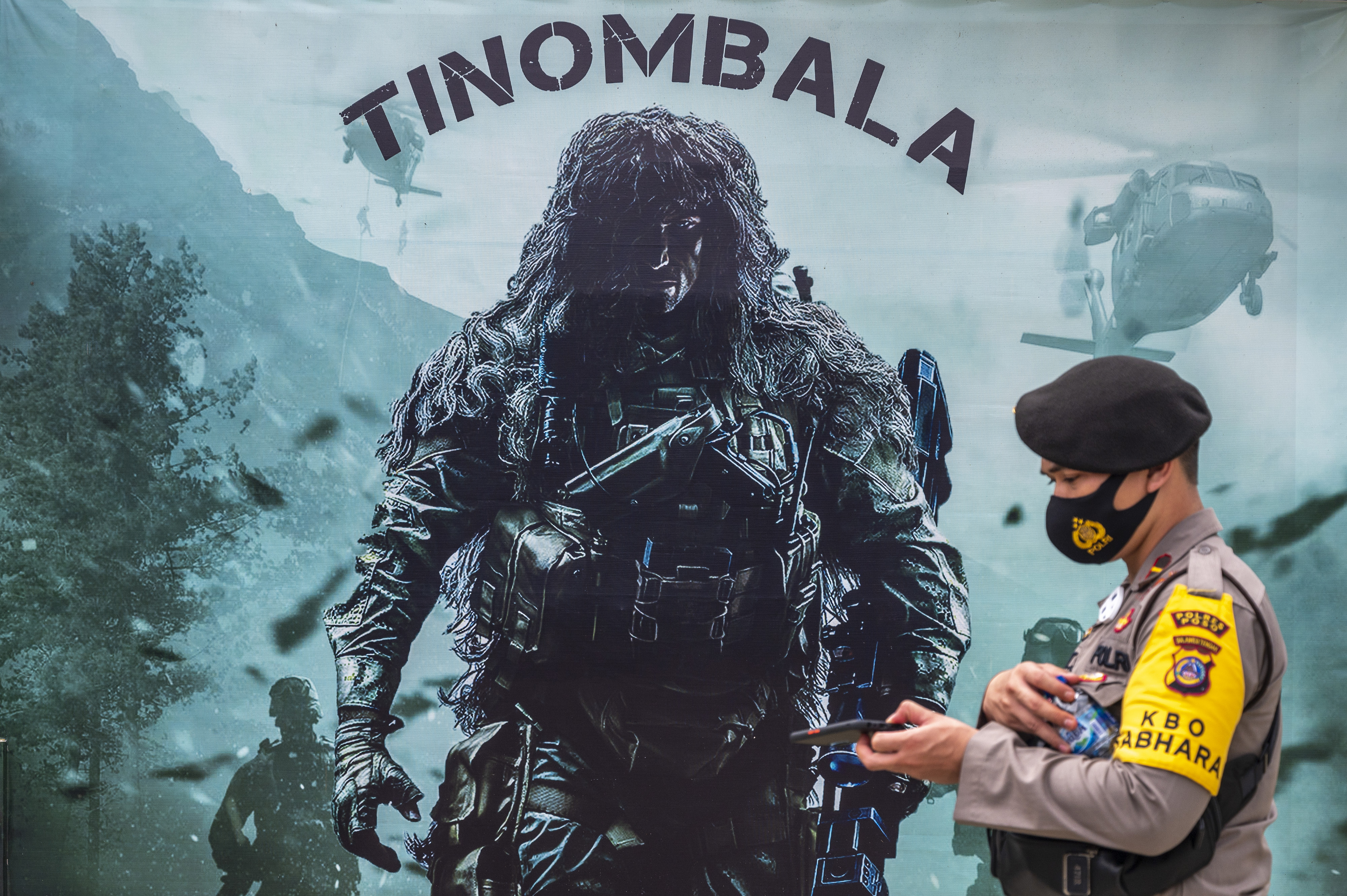 Seorang polisi melintas di depan baliho di Poskotis Satgas Tinombala di Desa Tokorondo, Poso Pesisir, Kabupaten Poso, Sulawesi Tengah.