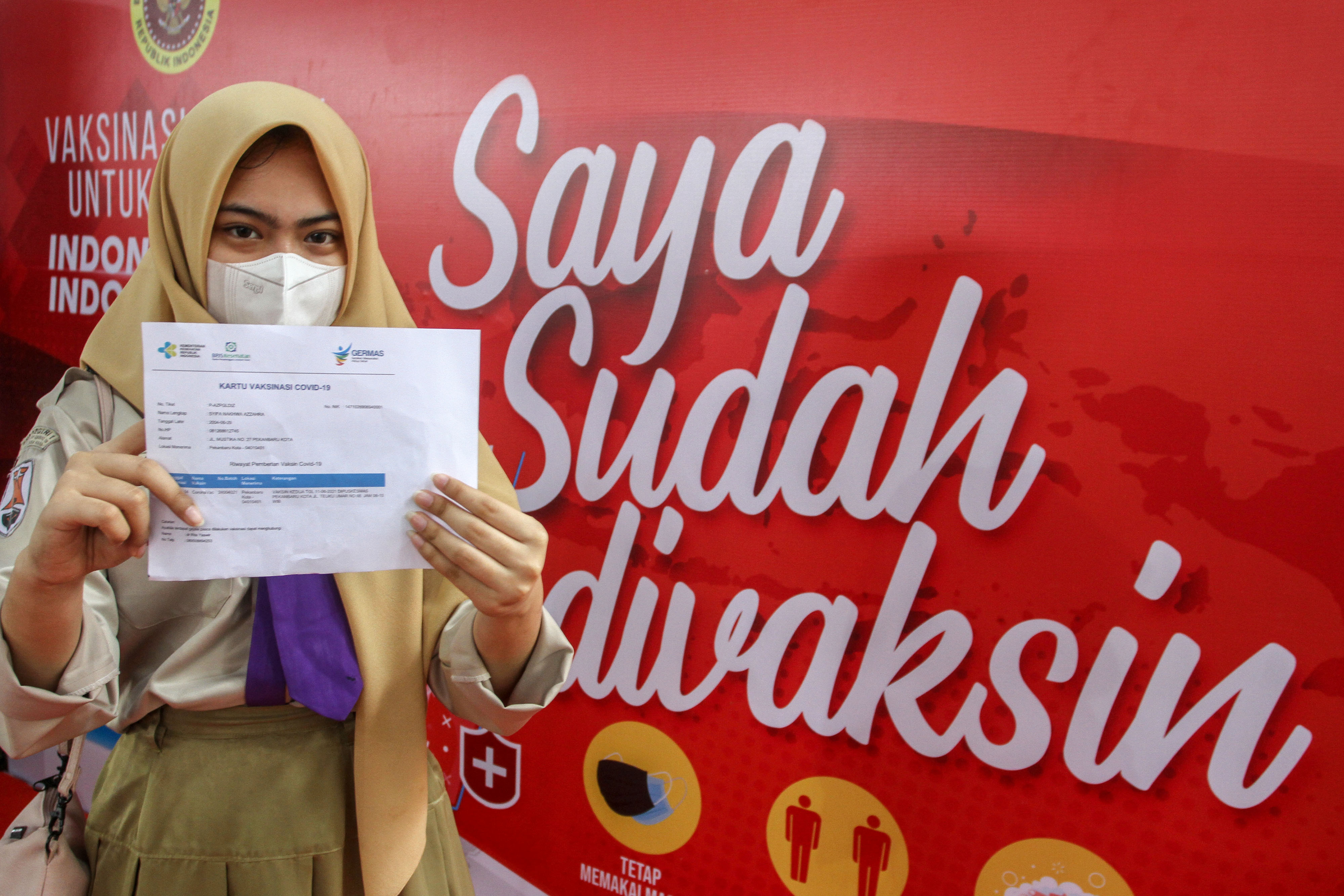 Seorang pelajar memperlihatkan kartu vaksinasi usai mendapatkan suntikkan vaksin COVID-19 di SMAN 1 Kota Pekanbaru, Riau, Rabu (14/7/2021).