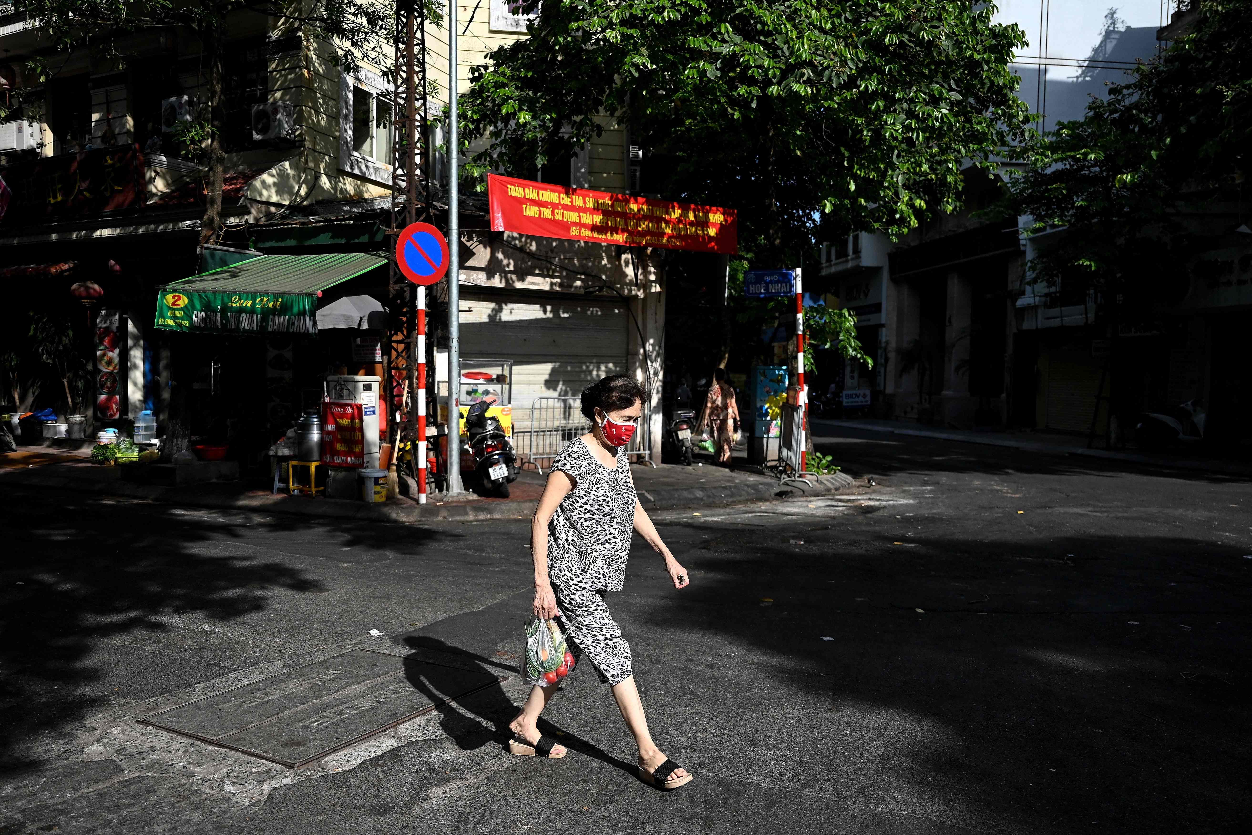 Seorang warga mengenakan masker melintas di jalan Kota Hanoi, Vietnam.