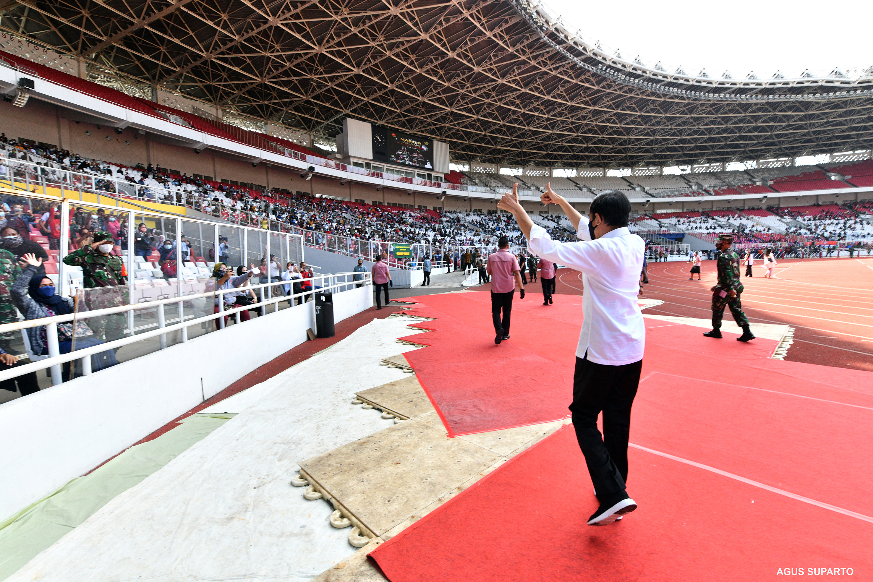 Presiden Joko Widodo menyapa ribuan warga yang sedang antre untuk mengikuti vaksinasi massal di Gelora Bung Karno, Jakarta, Minggu (25/6).