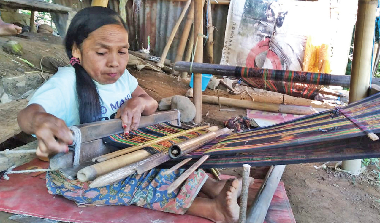 Marta Ndao, 40, penyandang disabilitas bertubuh pendek, tengah menenun sarung di rumahnya di Roworena Barat, Kecamatan Ende Utara.
