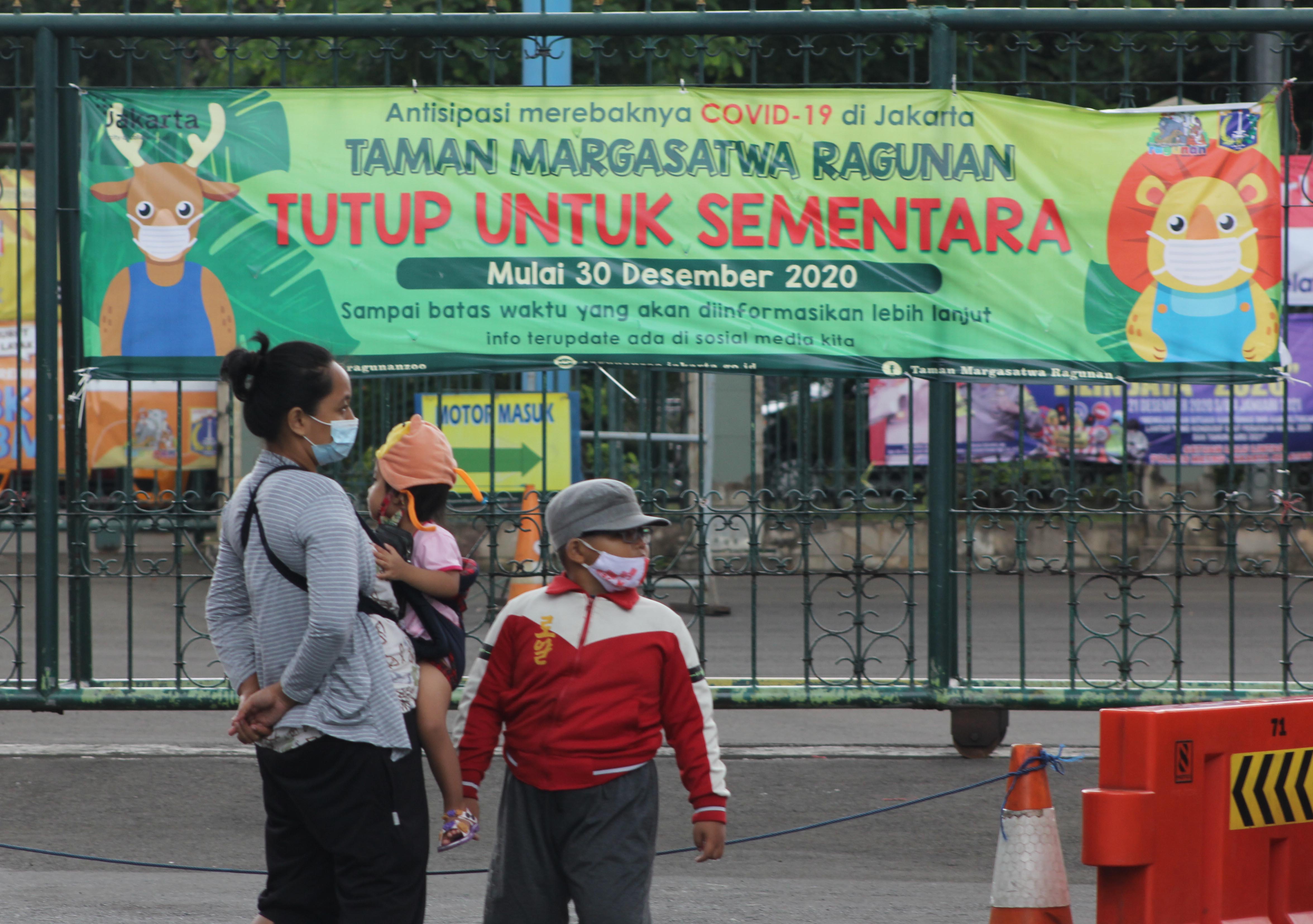 Ibu dan anak berada di depan pintu gerbang utaman objek wisata favorit Warga DKI Jakarta dan sekitarnya, Kebun Binatang Ragunan, Jakarta.