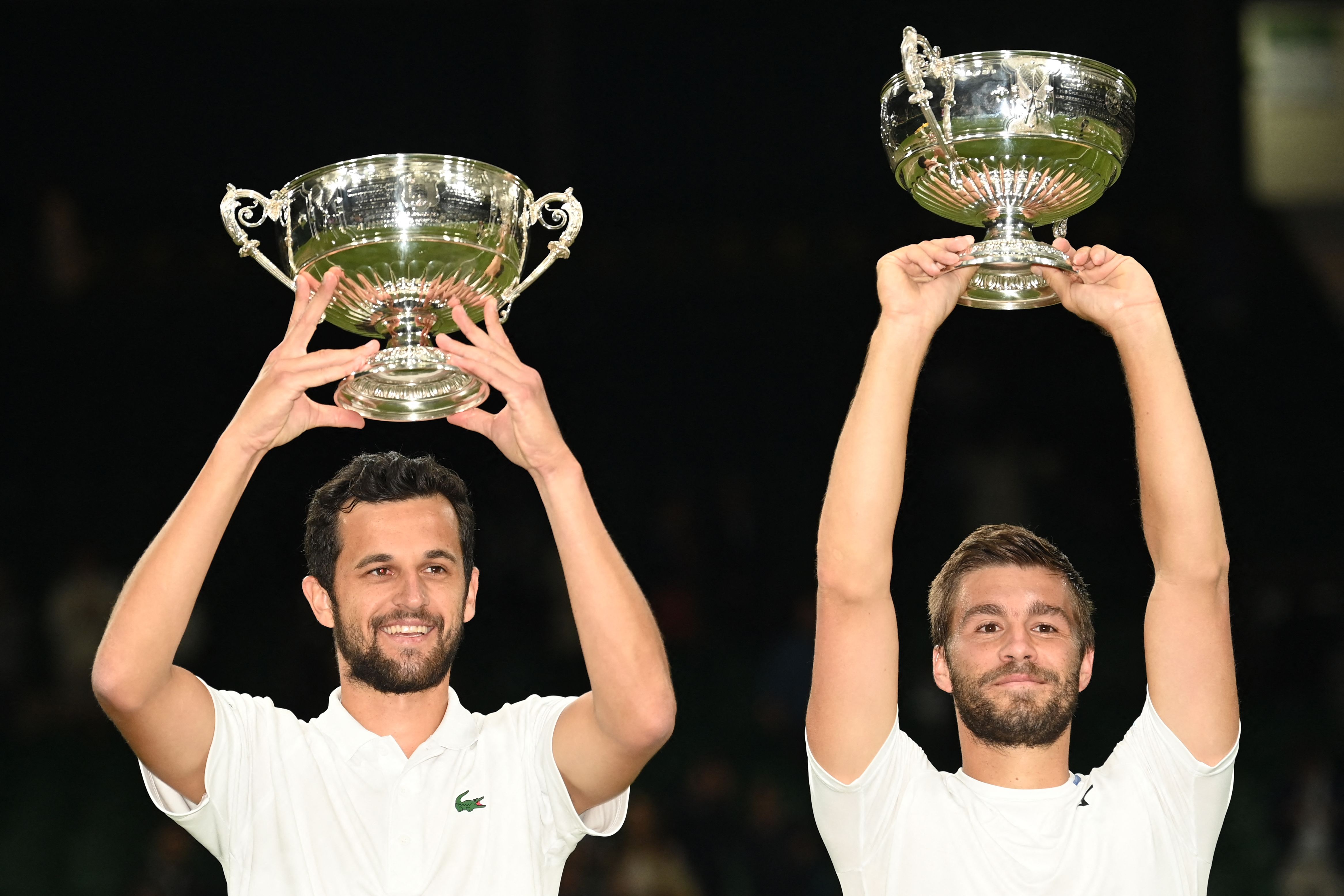 Pasangan Kroasia Nikola Mektic (kanan) dan Mate Pevic mengangkat trofi juara ganda putra Wimbledon.