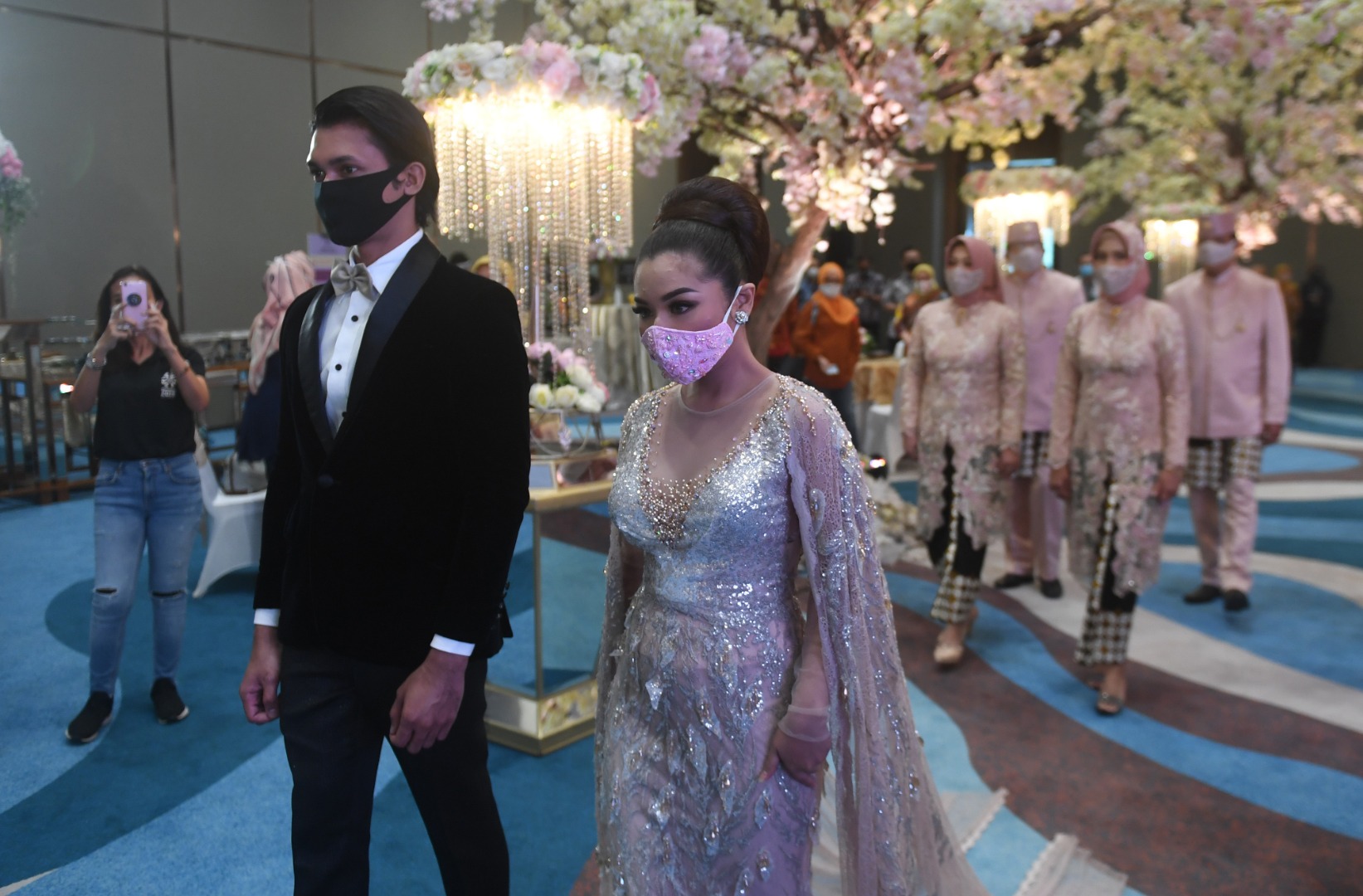 Pasangan pengantin mengenakan masker dalam simulasi pernikahan di era normal baru di Jakarta.