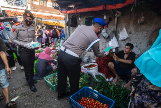 Pembagian masker saat pemberlakuan PPKM Darurat di Pasar Cisalak, Jawa Barat, Minggu (4/7/2021).