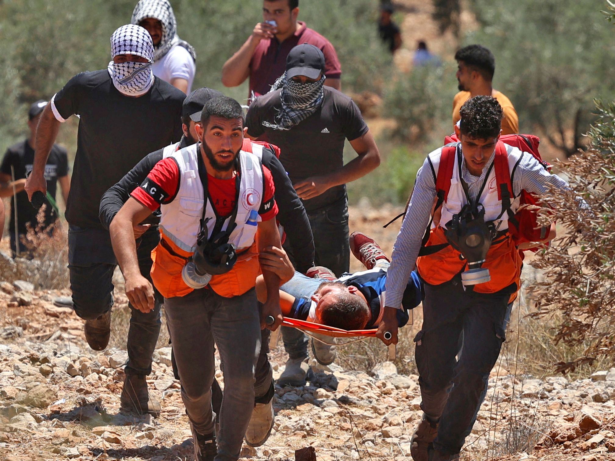 Petugas medis Bulan Sabit Merah Palestina mengevakuasi seorang pengunjuk rasa yang terluka selama bentrokan dengan pasukan Israel.
