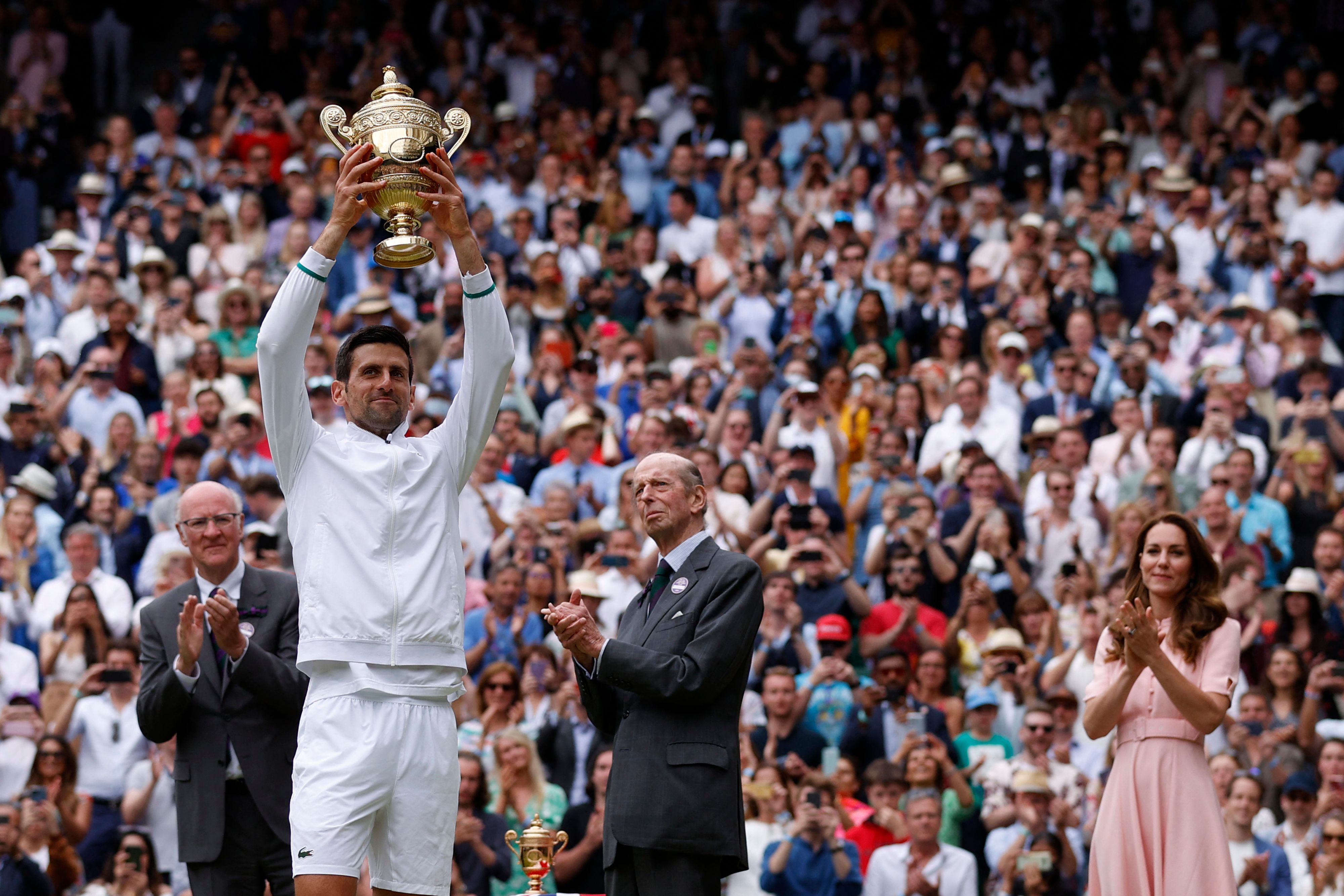 Petenis Serbia Novak Djokovic mengangkat trofi setelah menjuarai Wimbledon 2021.
