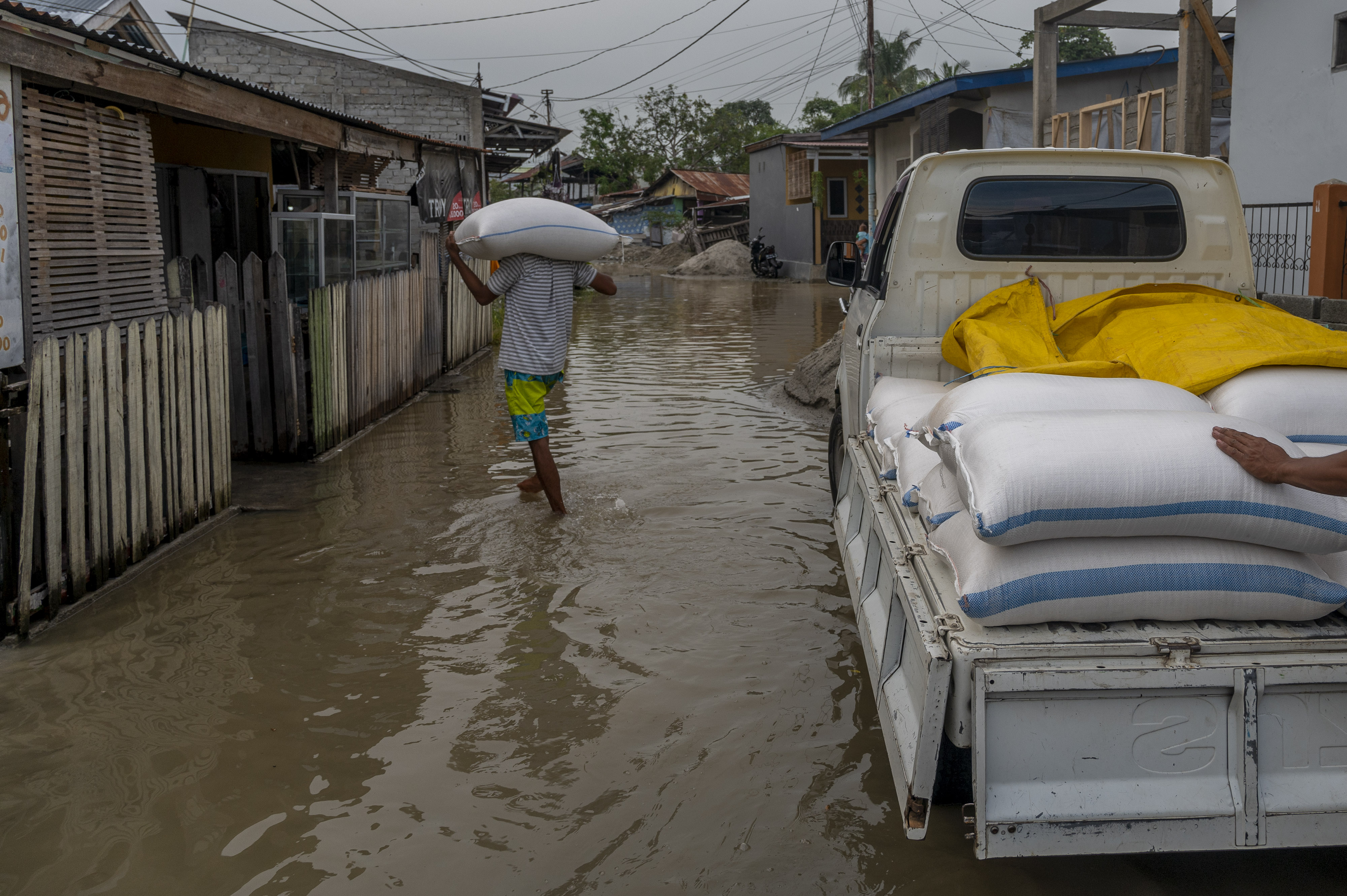 Warga memikul beras ke rumahnya yang digenangi air akibat sungai meluap di Kelurahan Baru, Palu, Sulawesi Tengah, kemarin