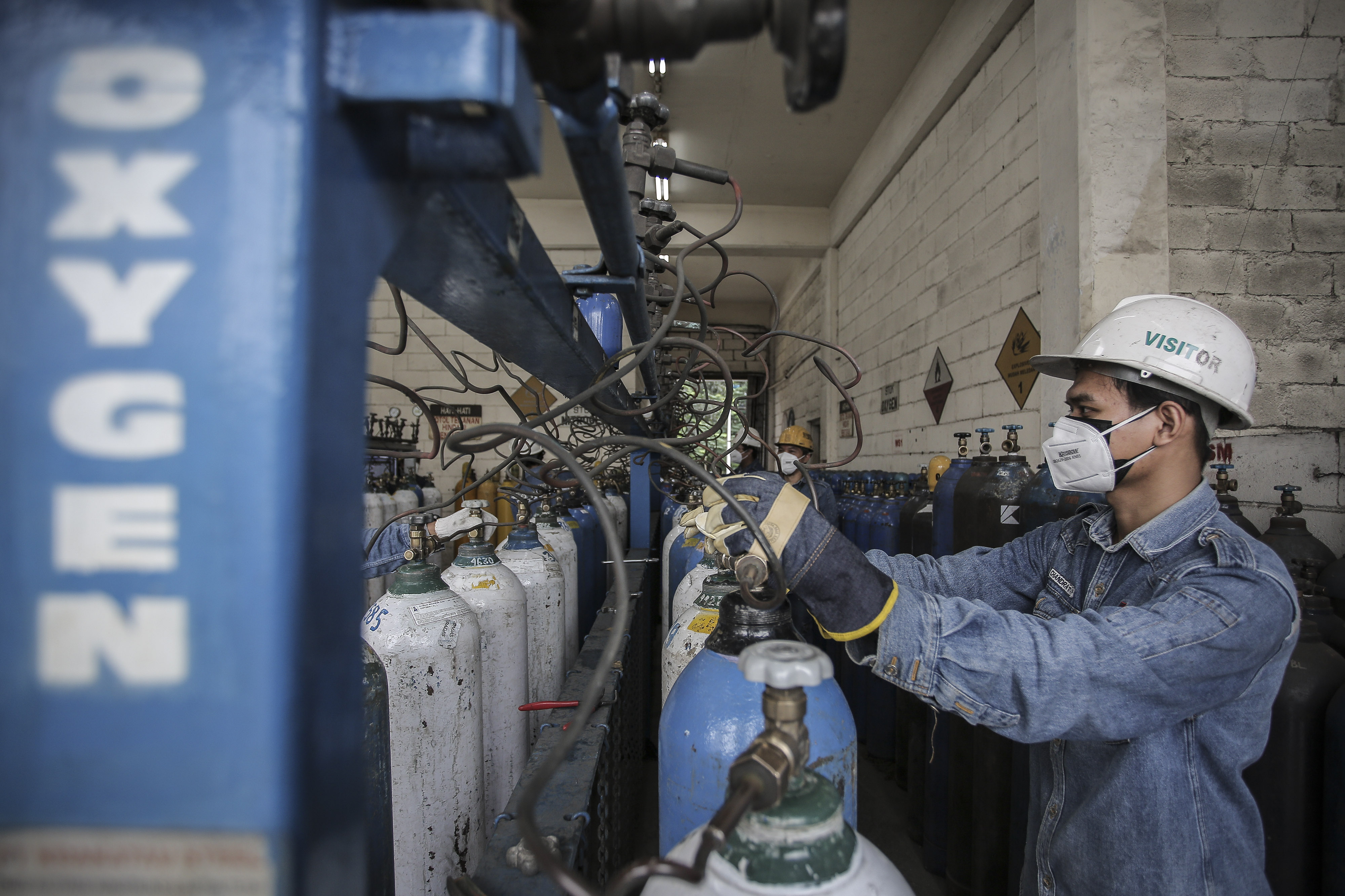 Petugas sedang mengisi ulang tabung oksigen.