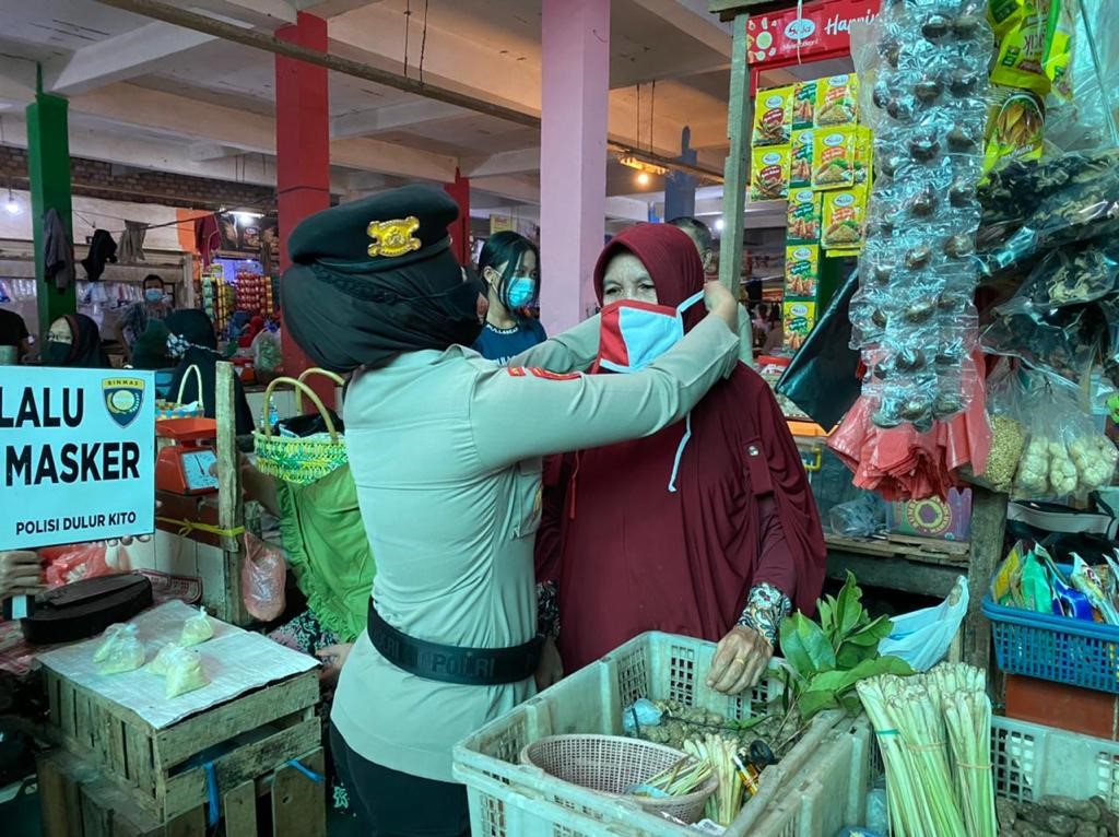 Personel dari Polda Sumsel dan TNI mengedukasi pentingnya protokol kesehatan dan membagikan masker di Pasar Modern Plaju Palembang.