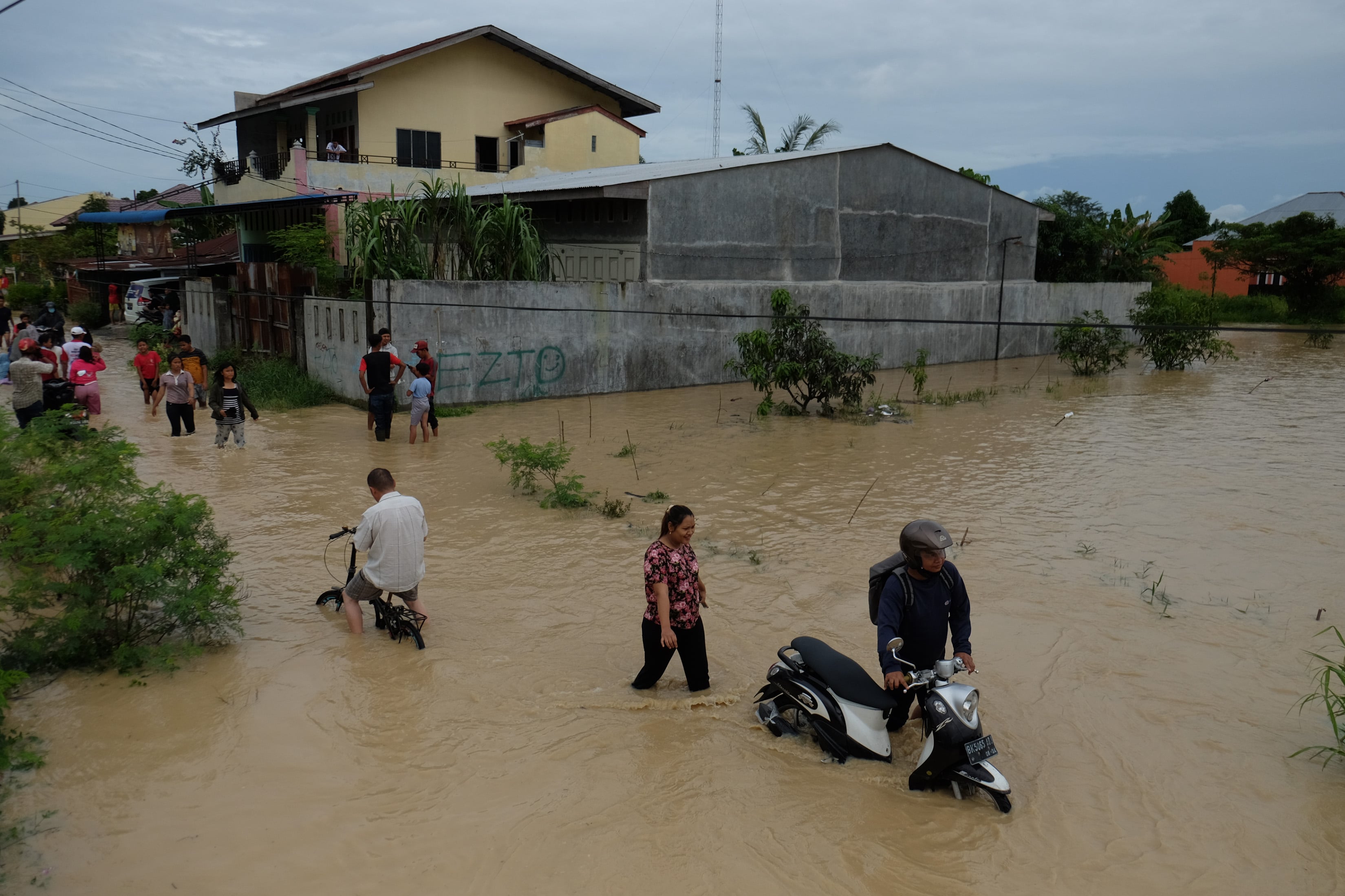 Ilustrasi warga melintasi banjir yang merendam pemukiman di wilayah Sumatera Utara.