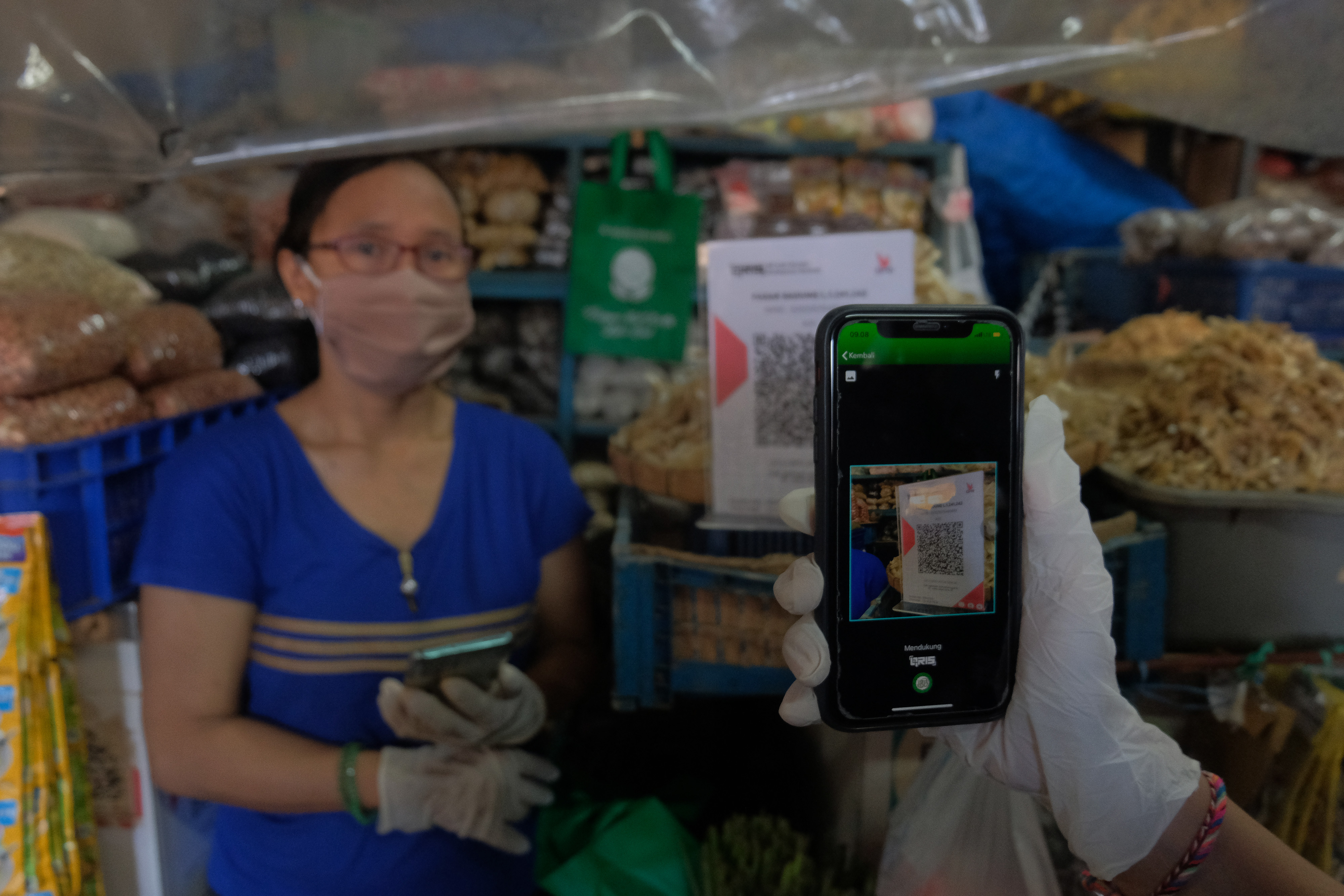 Konsumen melakukan pembayaran menggunakan fitur scan QRIS di Pasar Badung, Denpasar, Bali, Selasa (29/6/2021).