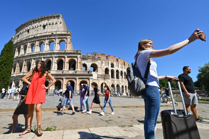 Dengan tanpa memakai masker, seorang wanita selfie di depan Colosseum di Roma, Italia, pada Sabtu (12/6 )