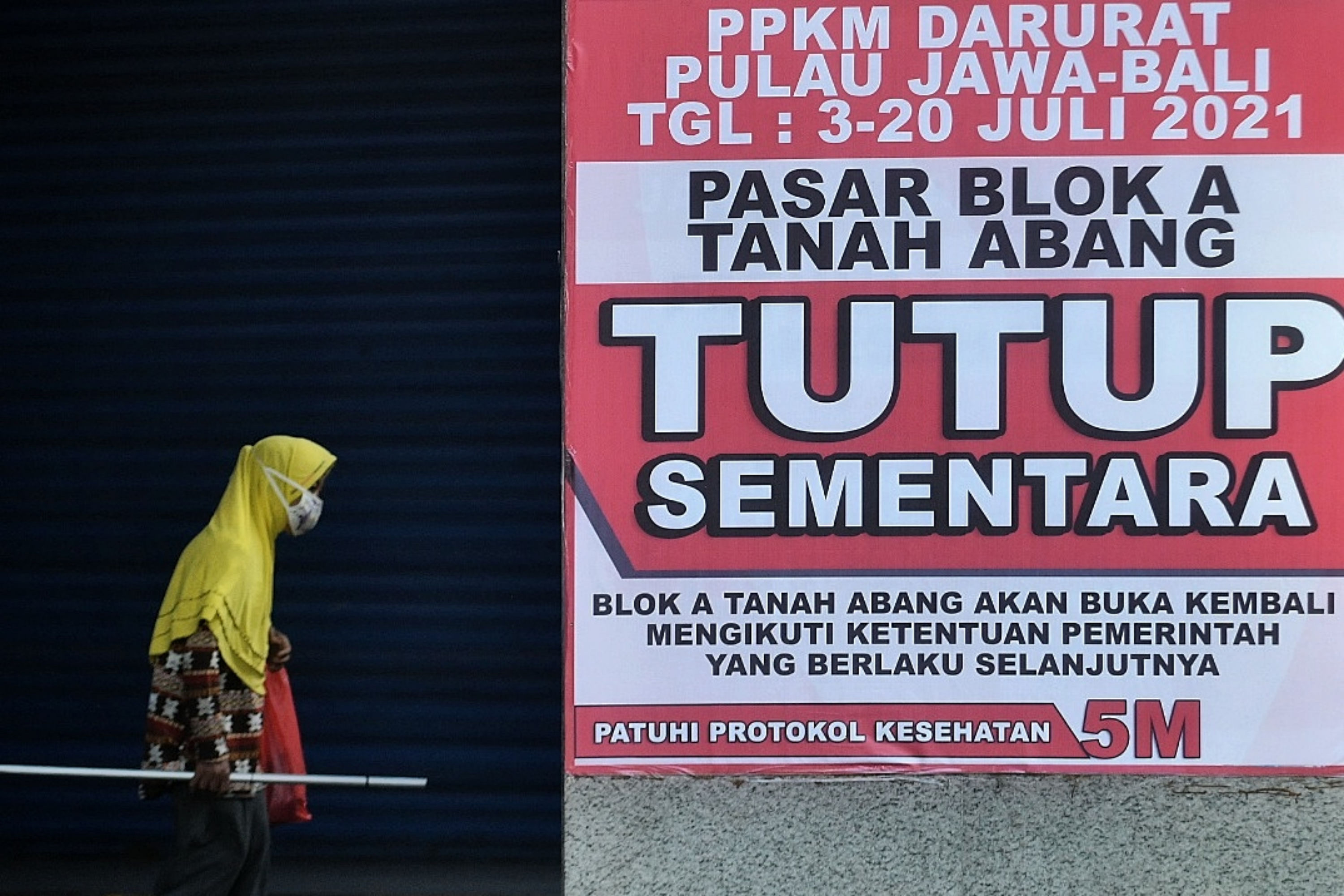 Warga melintas di dekat Pasar Tanah Abang yang tutup saat Pemberlakuan Pembatasan Kegiatan Masyarakat (PPKM) Darurat