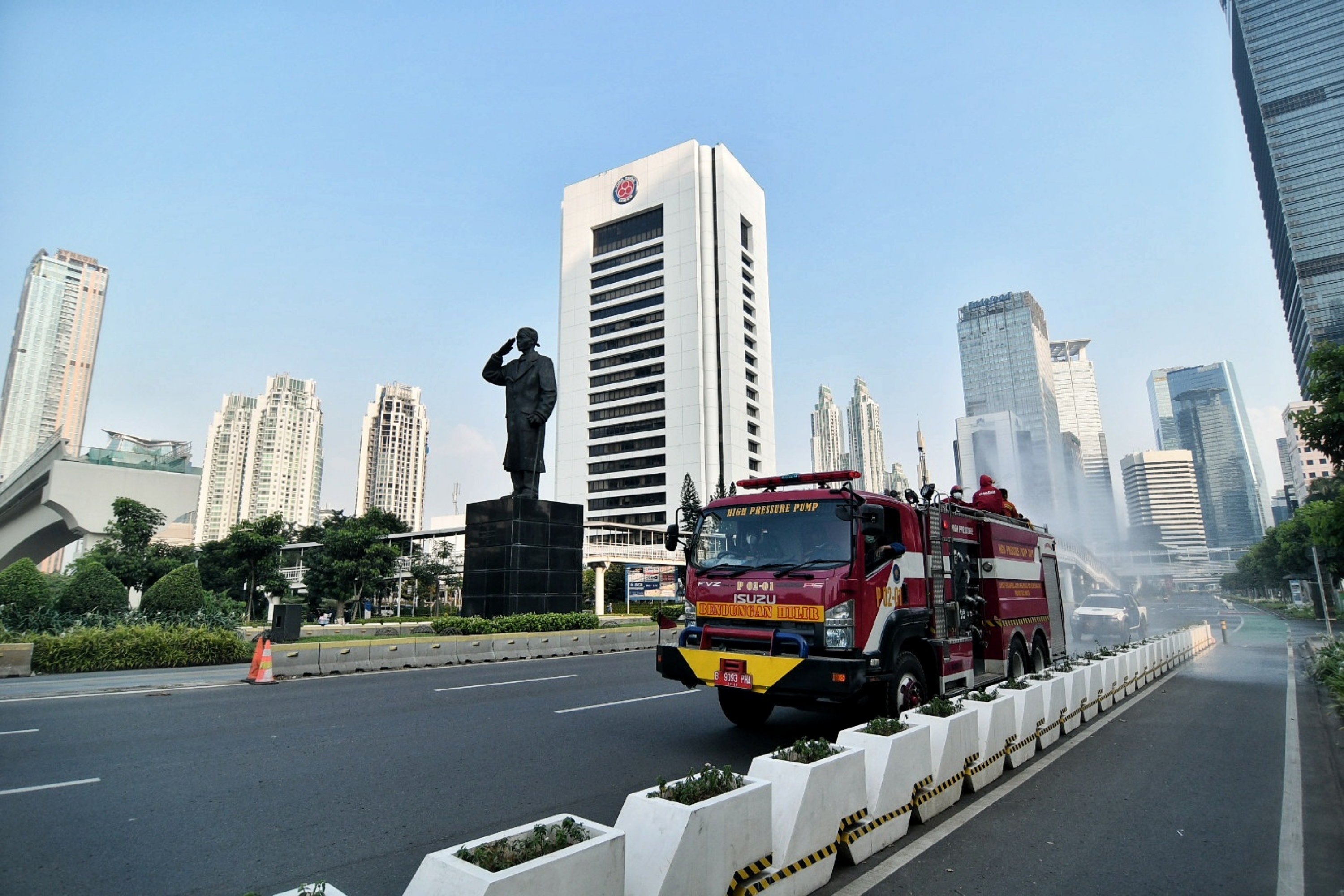 Petugas pemadam kebakaran menyemprotkan cairan disinfektan di kawasan Sudirman, Jakarta.