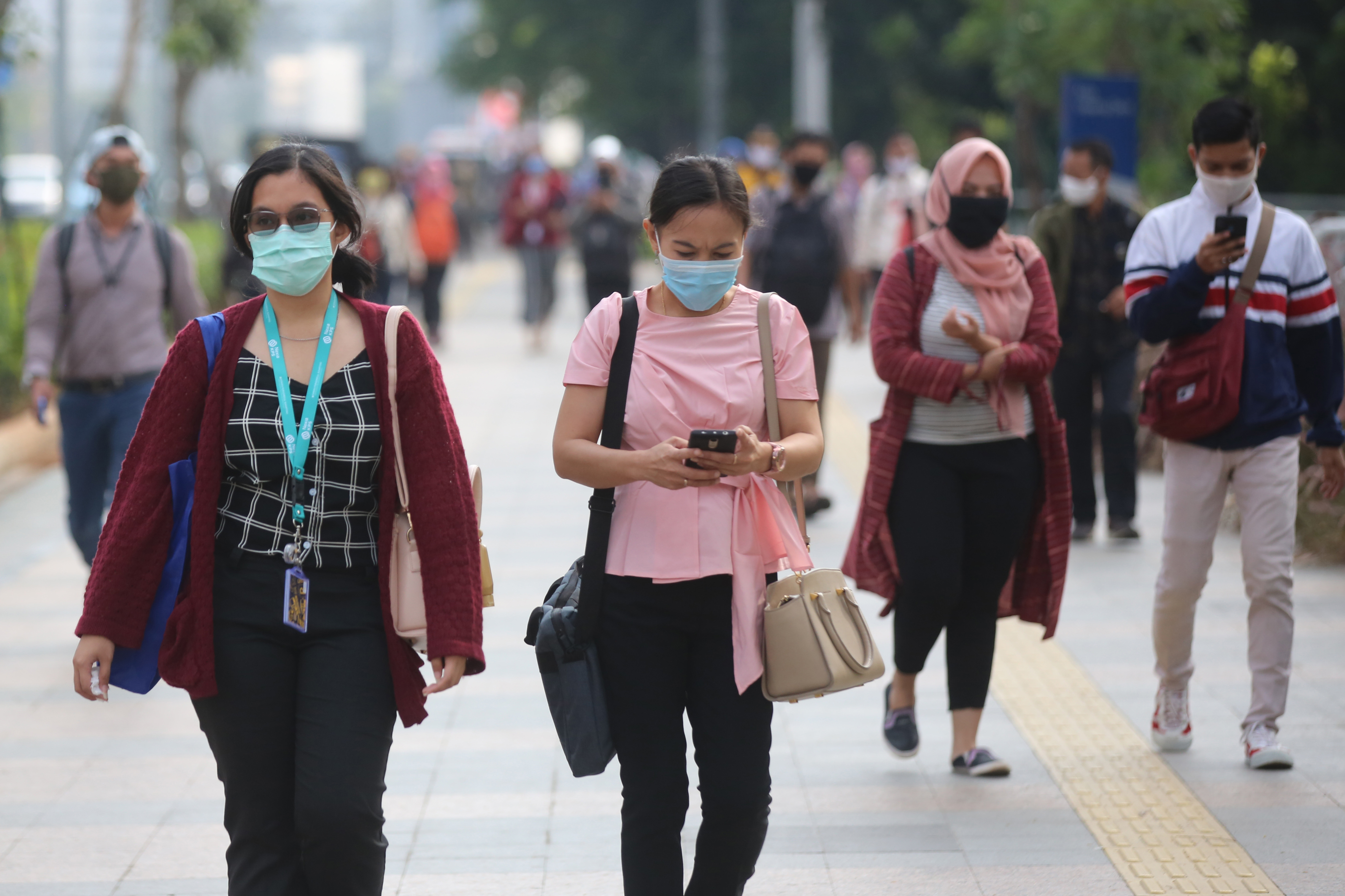 Pekerja menggunakan masker saat menuju ke kantor 