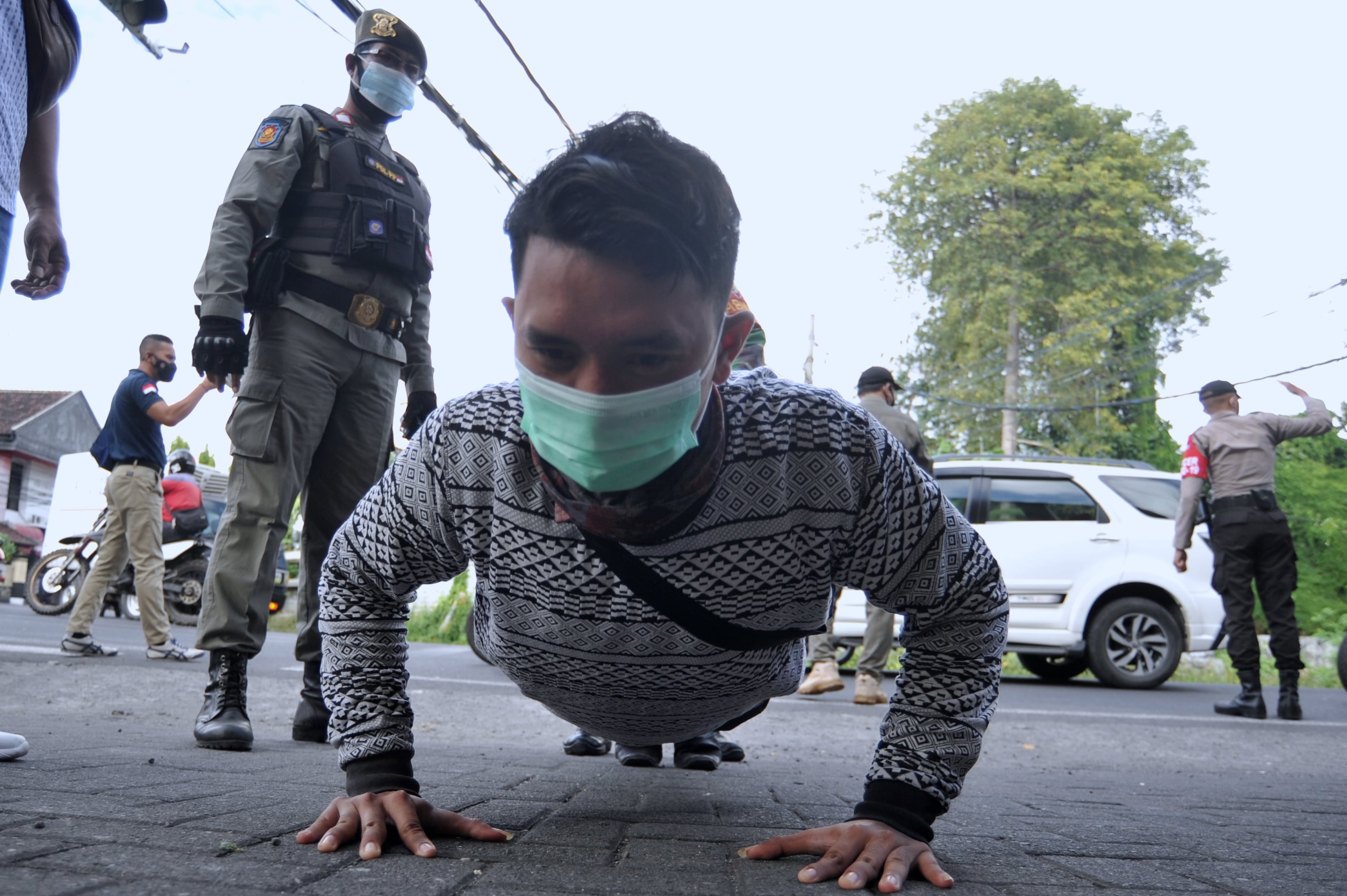 Petugas menghukum warga pelanggar protokol kesehatan (prokes) saat sidak PPKM di Denpasar, Bali, hari ini.