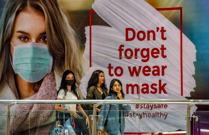 Pengunjung berjalan di depan pesan visual bertuliskan ‘Don’t forget to wear a mask’ di Mal Pondok Indah, Jakarta.