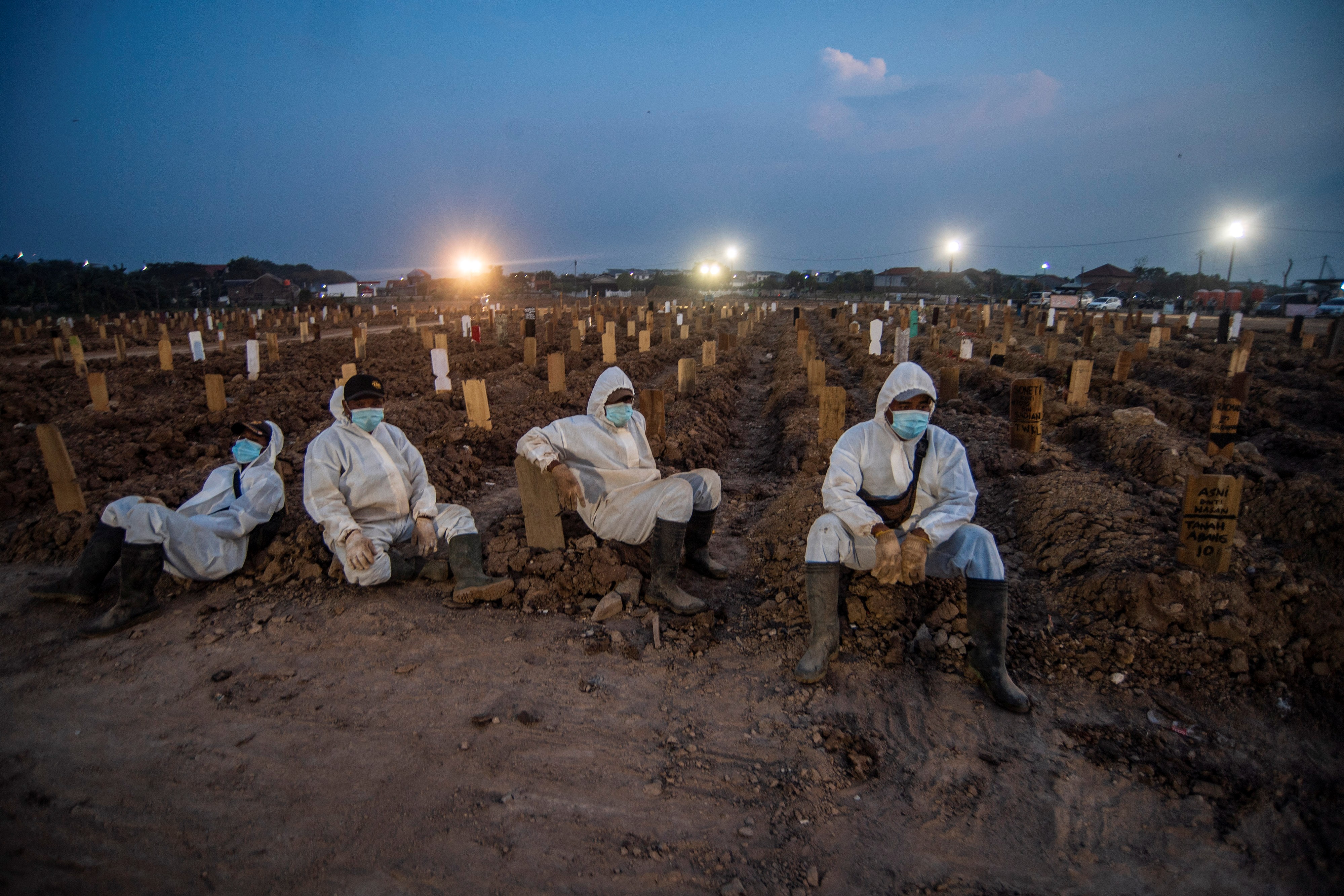 Petugas pemakaman beristirahat usai memakamkan sejumlah jenazah dengan protokol covid-19 di TPU Rorotan, Cilincing, Jakarta, Minggu (4/7).