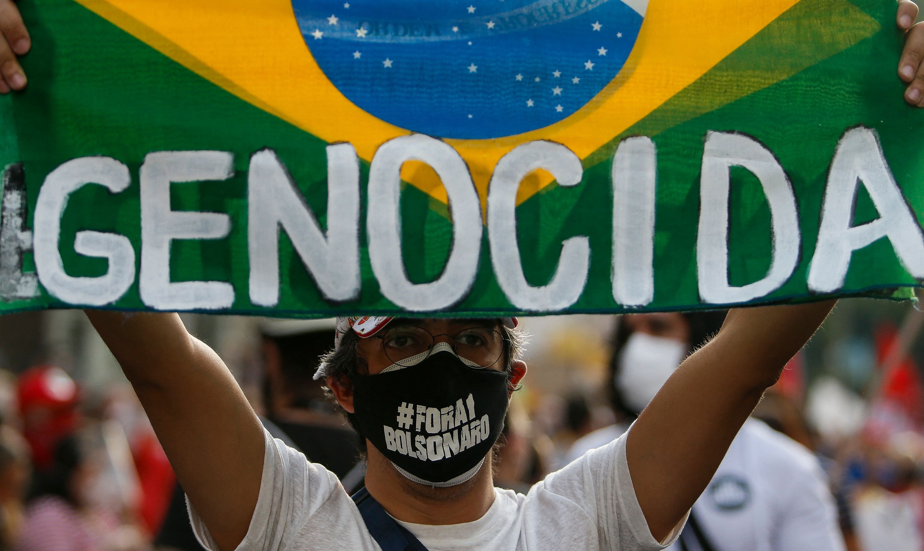 Demonstran membawa bendera Brasil dengan tulisan Genosida yang ditujukan untuk Bolsonaro