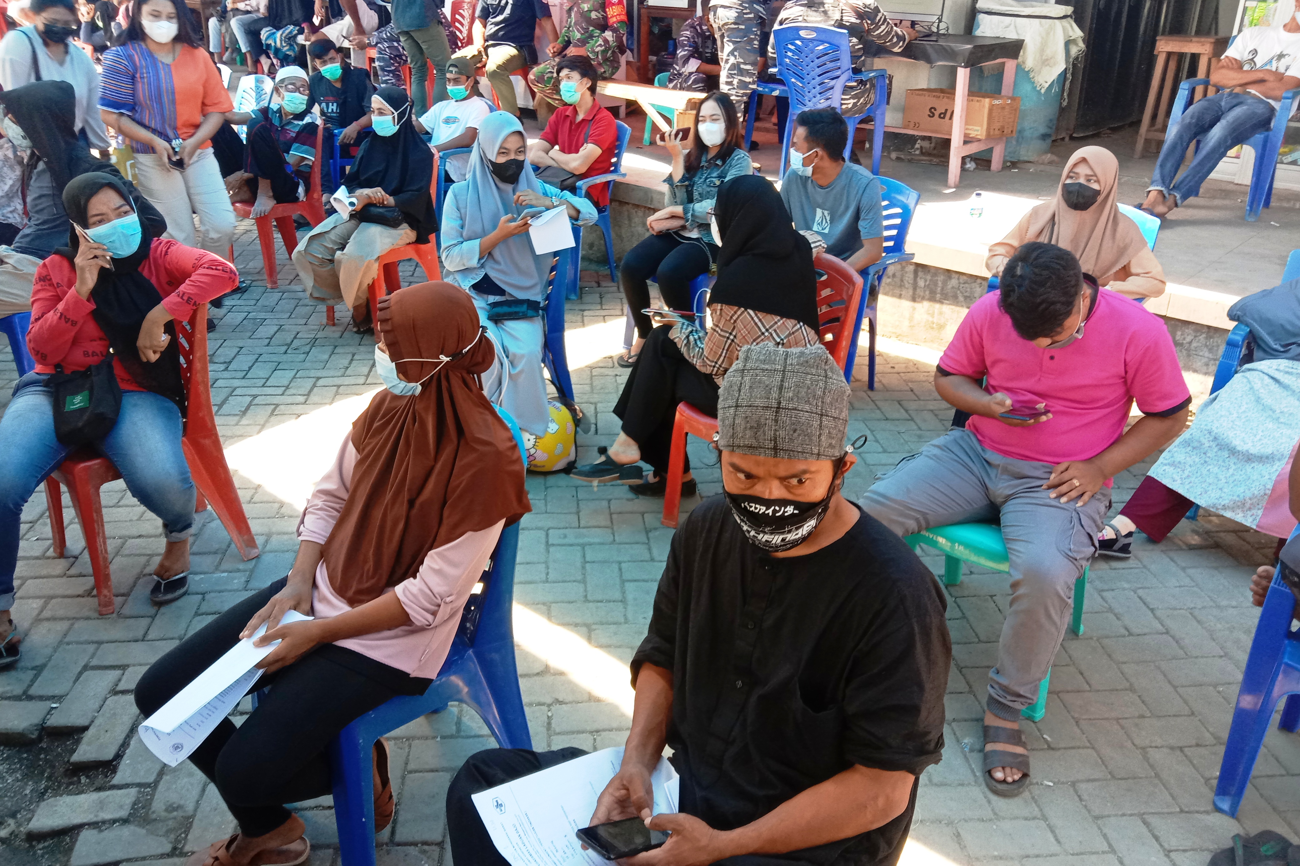 Warga antusias duduk bersiap menerima suntikan vaksin covid-19 yang di gelar TNI AL di TPI Kelurahan Labuan Bajo.