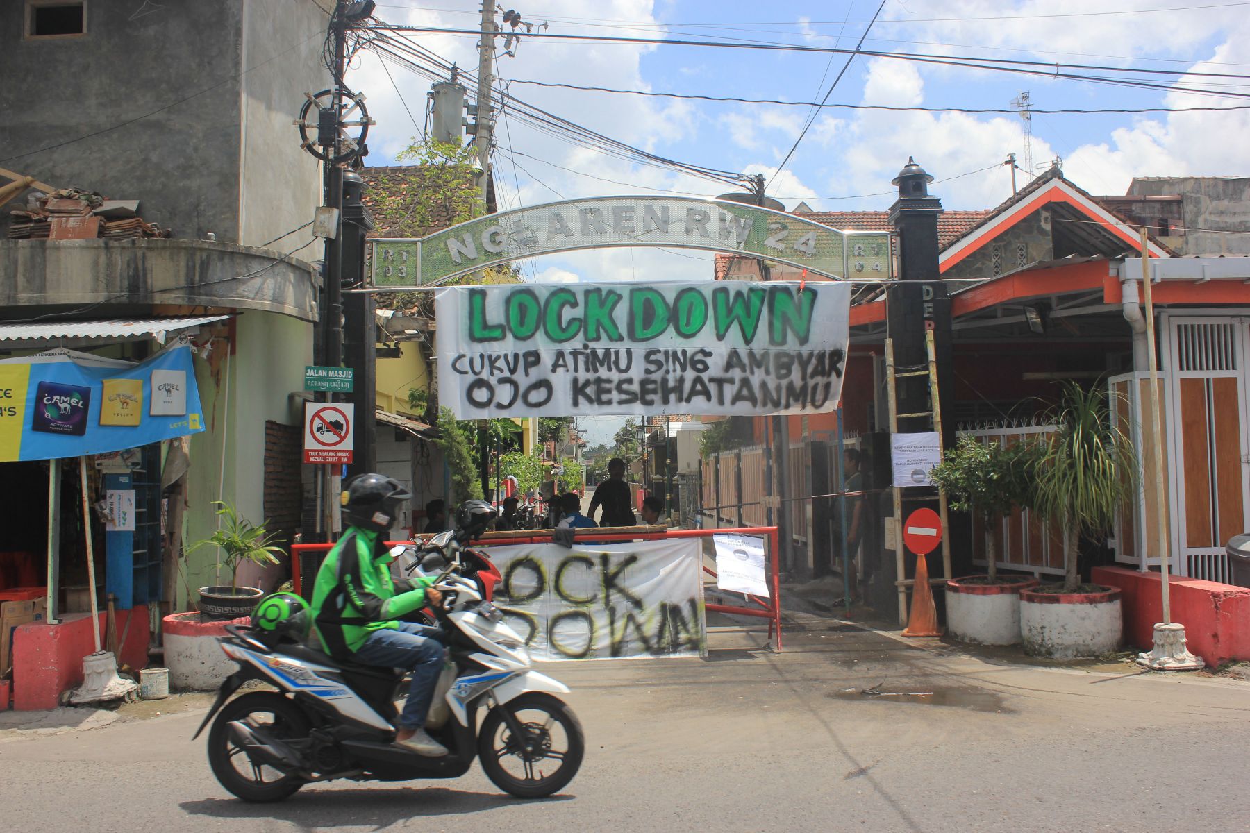 Seorang pengemudi ojek online sedang melewati Dukuh Kropoh, Sleman, DIY, yang menutup akses masuk ke wilayah itu.