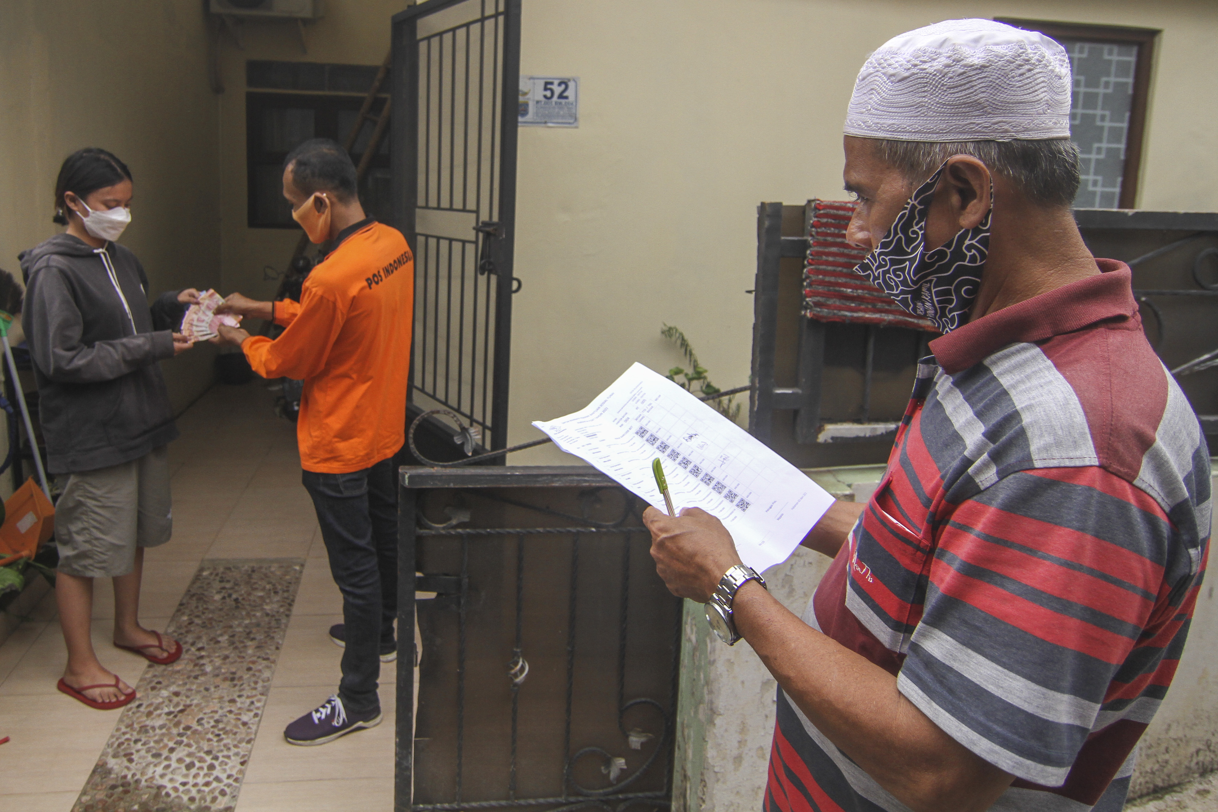 Juru Bayar Kantor Pos Indonesia (kanan) menyalurkan BST Kemensos kepada warga di wilayah Bojong Pondok Terong, Depok, Jawa Barat.