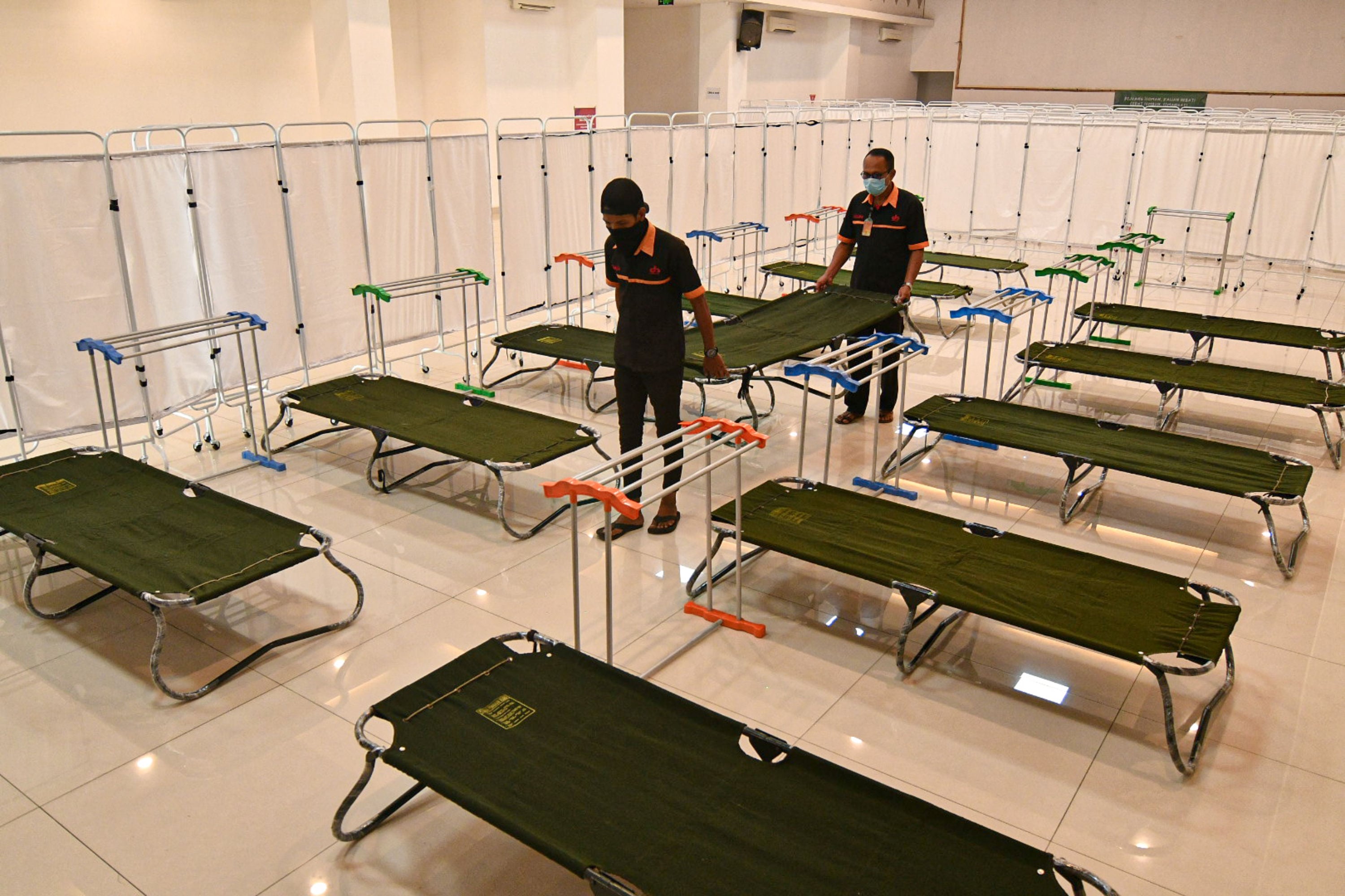  Petugas menyiapkan tempat isolasi pasien Covid-19 di Gelanggang Olahraga (GOR) Matraman, Jakarta, Rabu (14/7/2021).