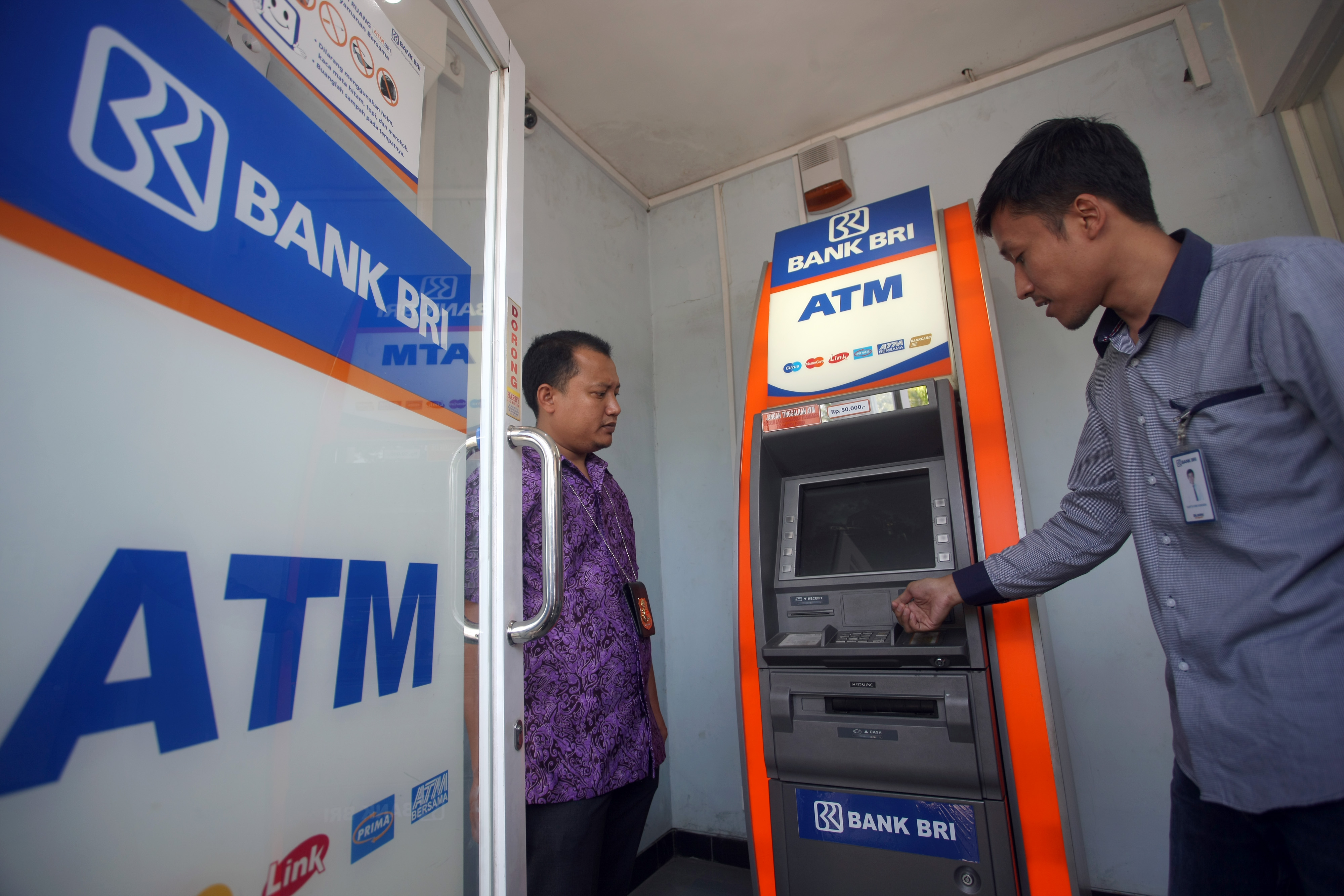 Ilustrasi petugas memeriksa mesin ATM milik Bank BRI.