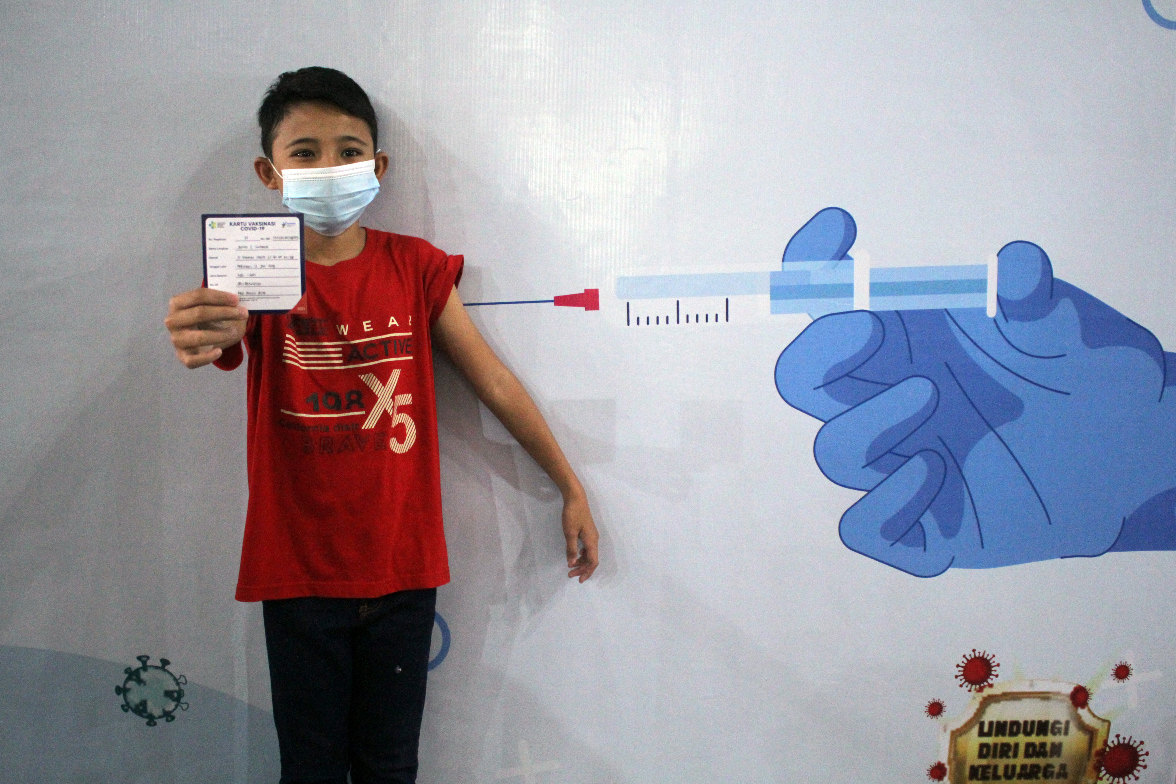 Ilustrasi seorang anak menunjukkan kartu vaksinasi covid-19.
