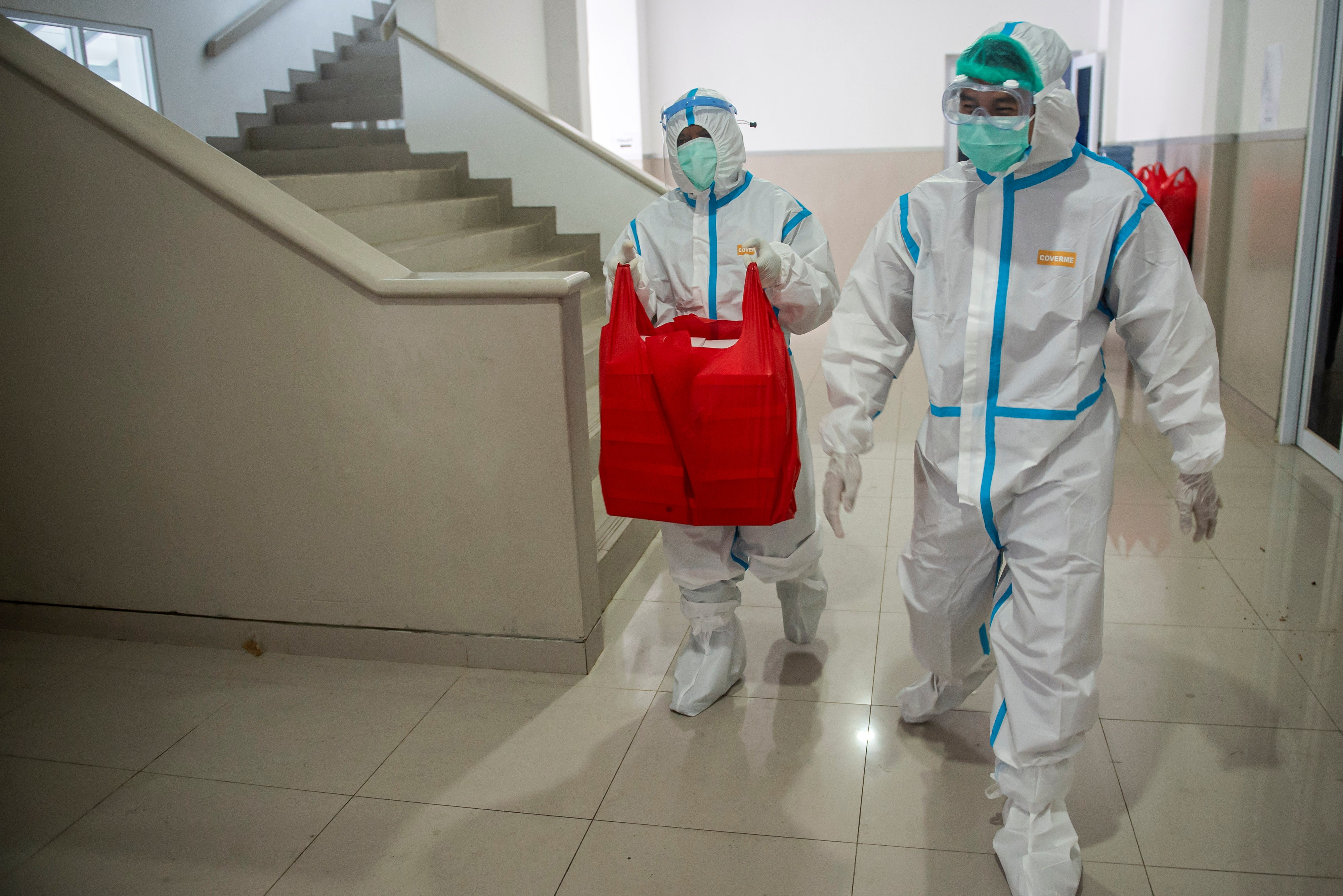 Dua tenaga kesehatan mengantarkan hidangan makan untuk pasien di ruang isolasi di Rumah Sakit Darurat Pangkalan Marinir Jakarta.