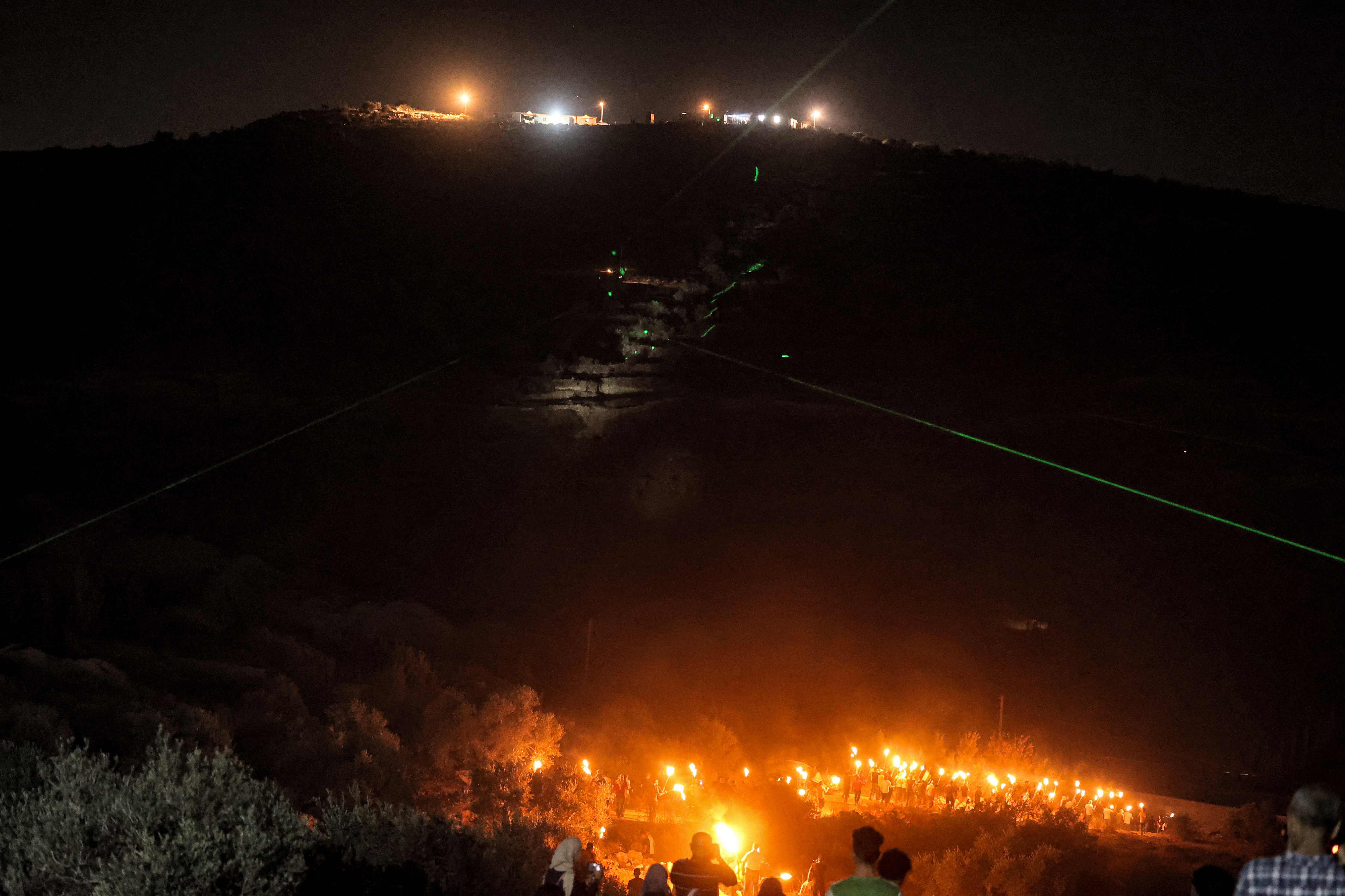 Pengunjuk rasa Palestina berkumpul dengan obor selama demonstrasi menentang pos pemukim Israel di Eviatar, di kota Beita, Rabu (30/6).