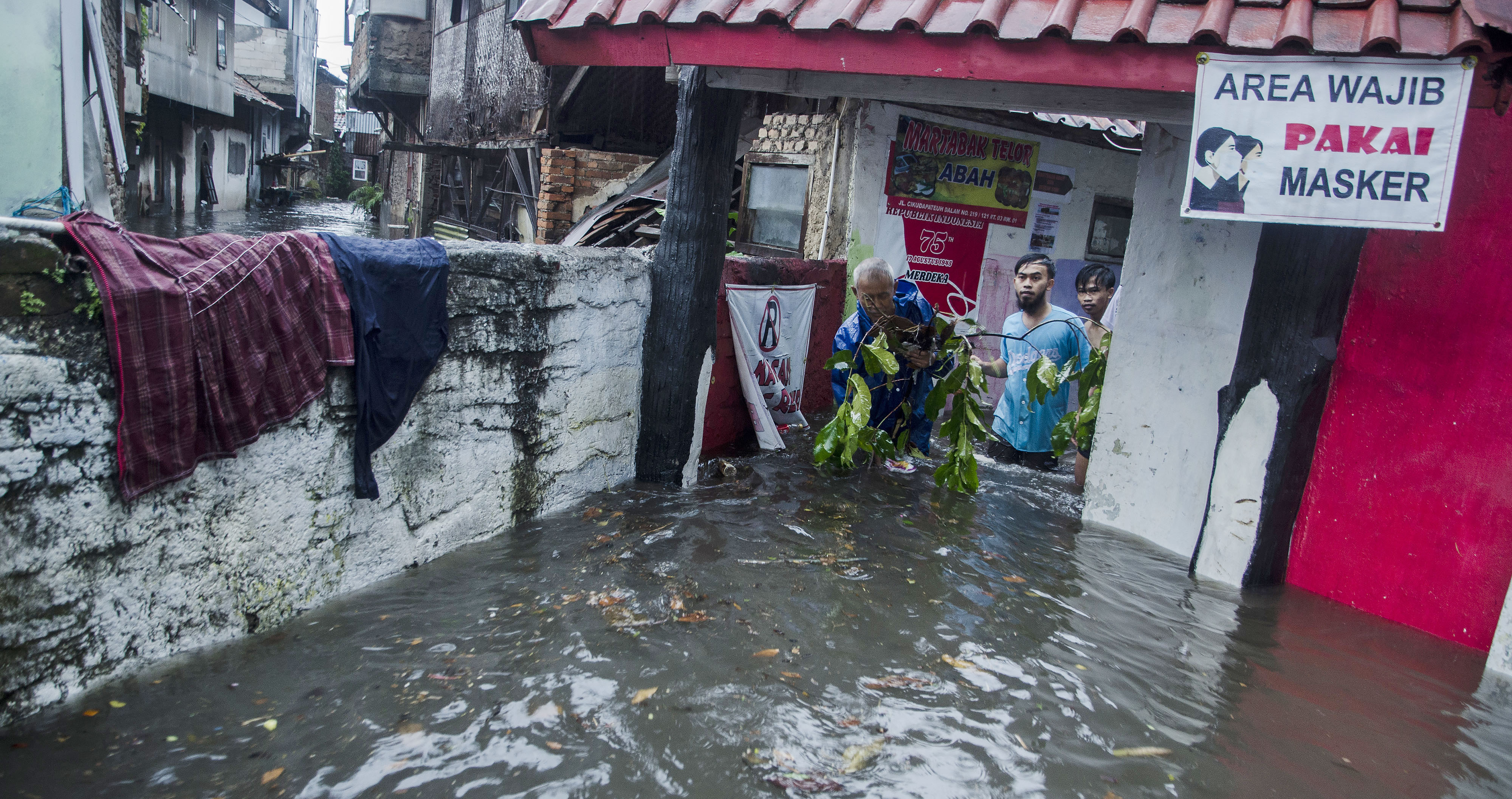 Warga membersihkan sampah yang terbawa arus banjir di kawasan Kacapiring, Bandung, Jawa Barat, Senin (21/6/2021).