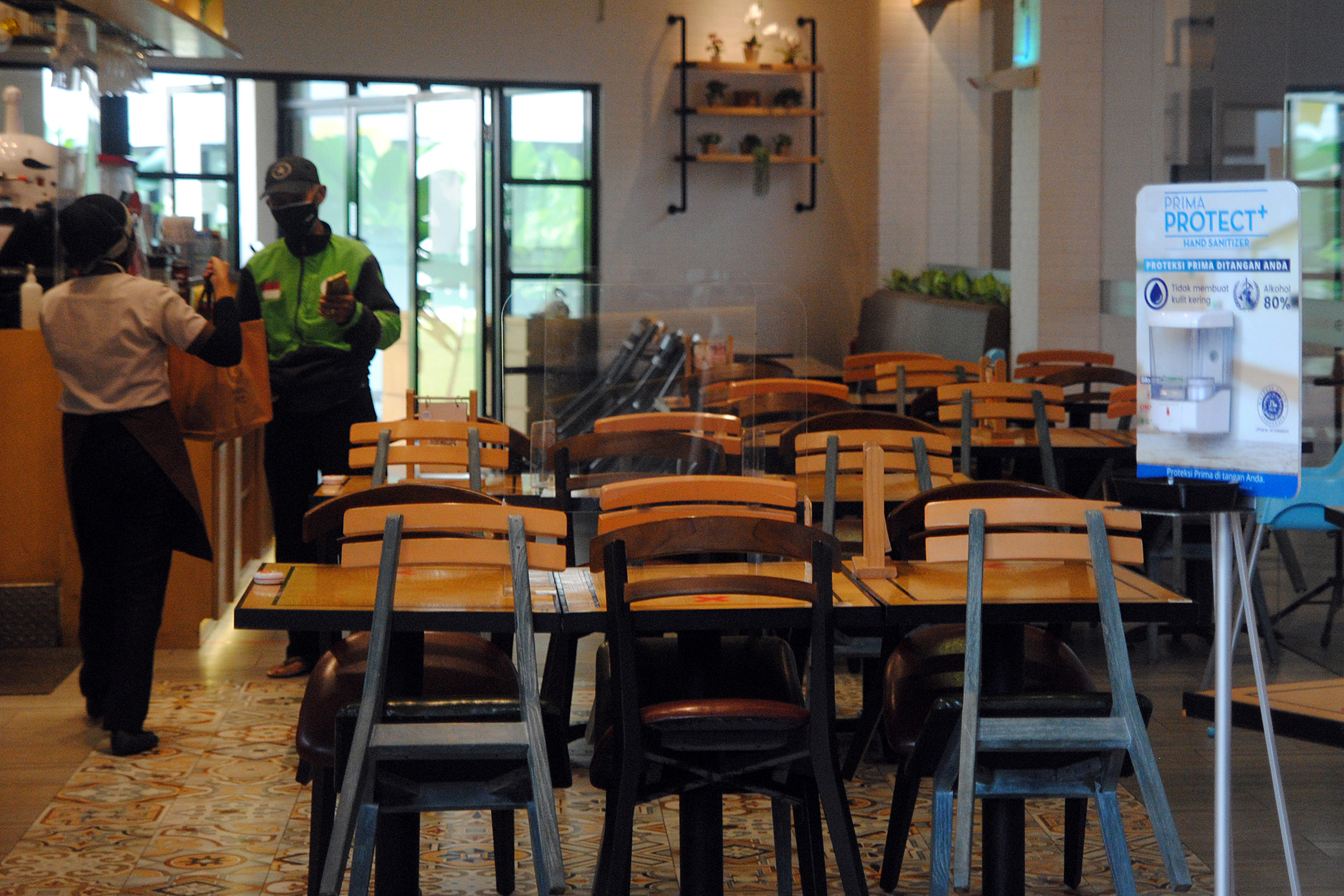 Pengemudi ojek daring mengambil pesanan makanan di salah satu restoran saat masa PPKM Darurat