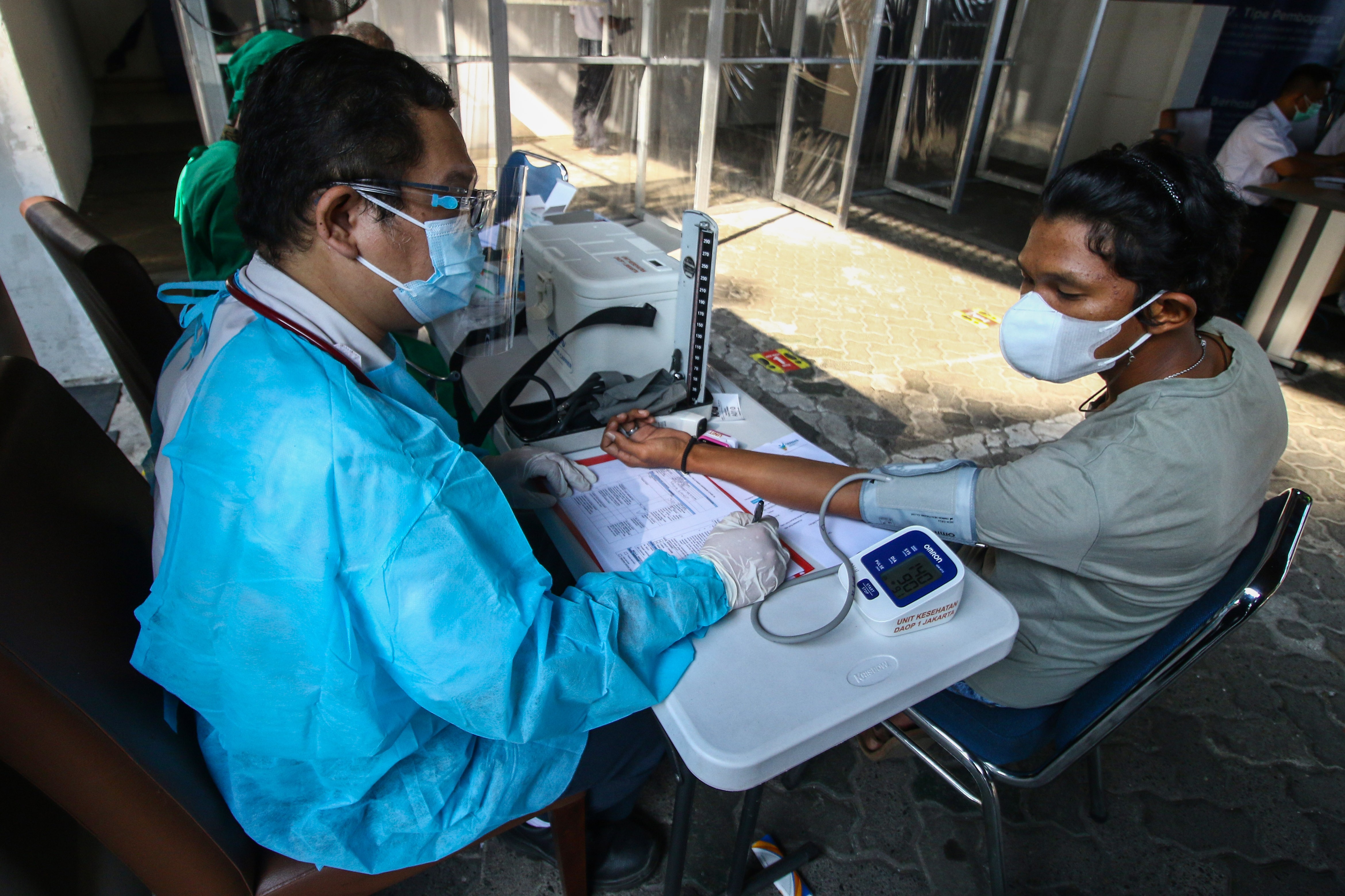 Tenaga kesehatan memeriksa kesehatan calon penumpang kereta sebelum disuntikkan vaksin covid-19 di Stasiun Gambir, Jakarta.