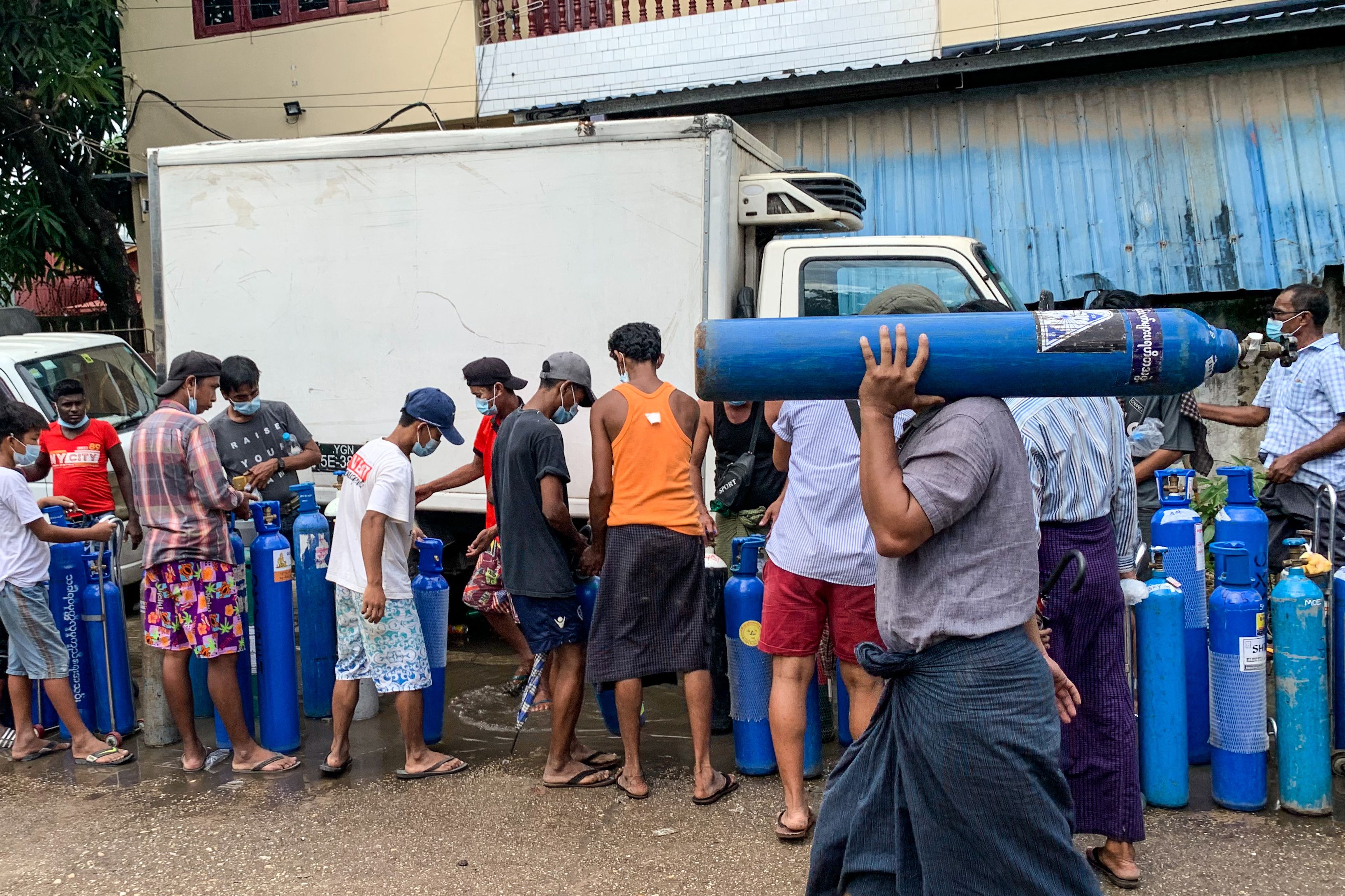 Warga mengantre untuk mengisi tabung oksigen untuk anggota keluarga yang terpapar Covid-19 di Yangon, Myanmar, Minggu (11/7). 