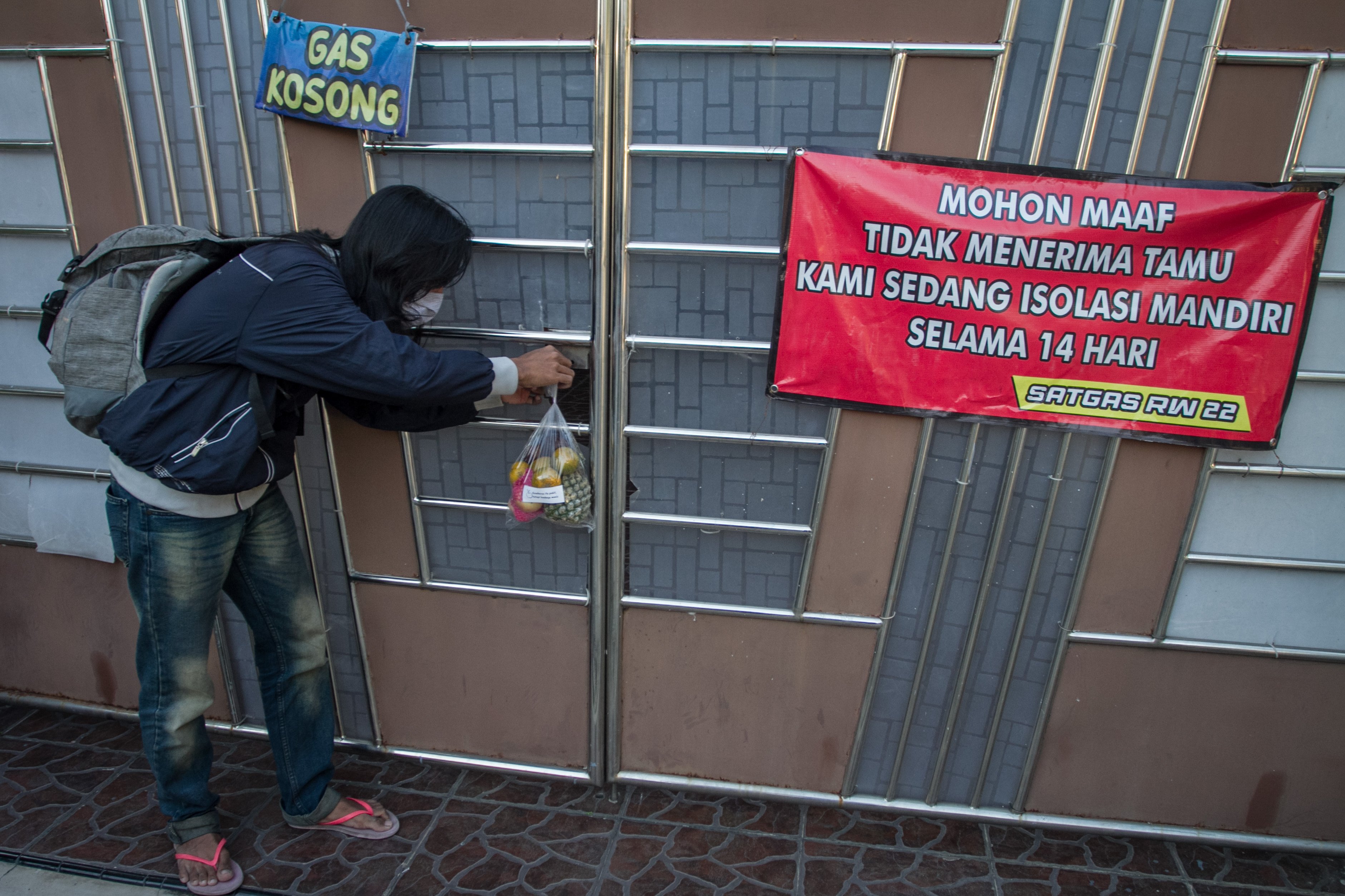 Relawan menggantungkan buah-buahan di pagar rumah warga yang sedang menjalani isolasi mandiri di Kampung Pucang Sawit, Solo, Jawa Tengah.