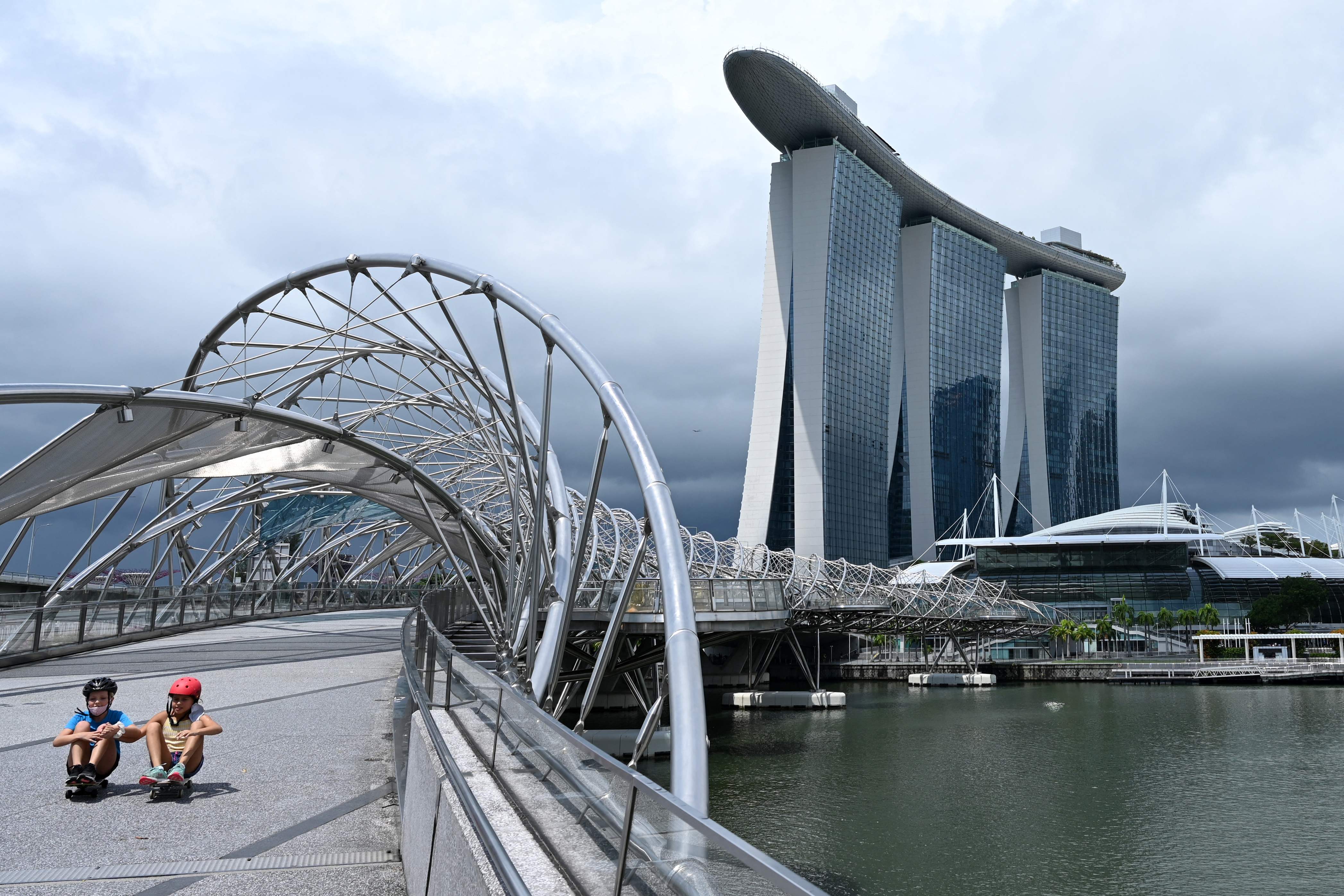 Anak-anak tengah bermain skateboards di Helix bridge di Marina Bay, Singapura.