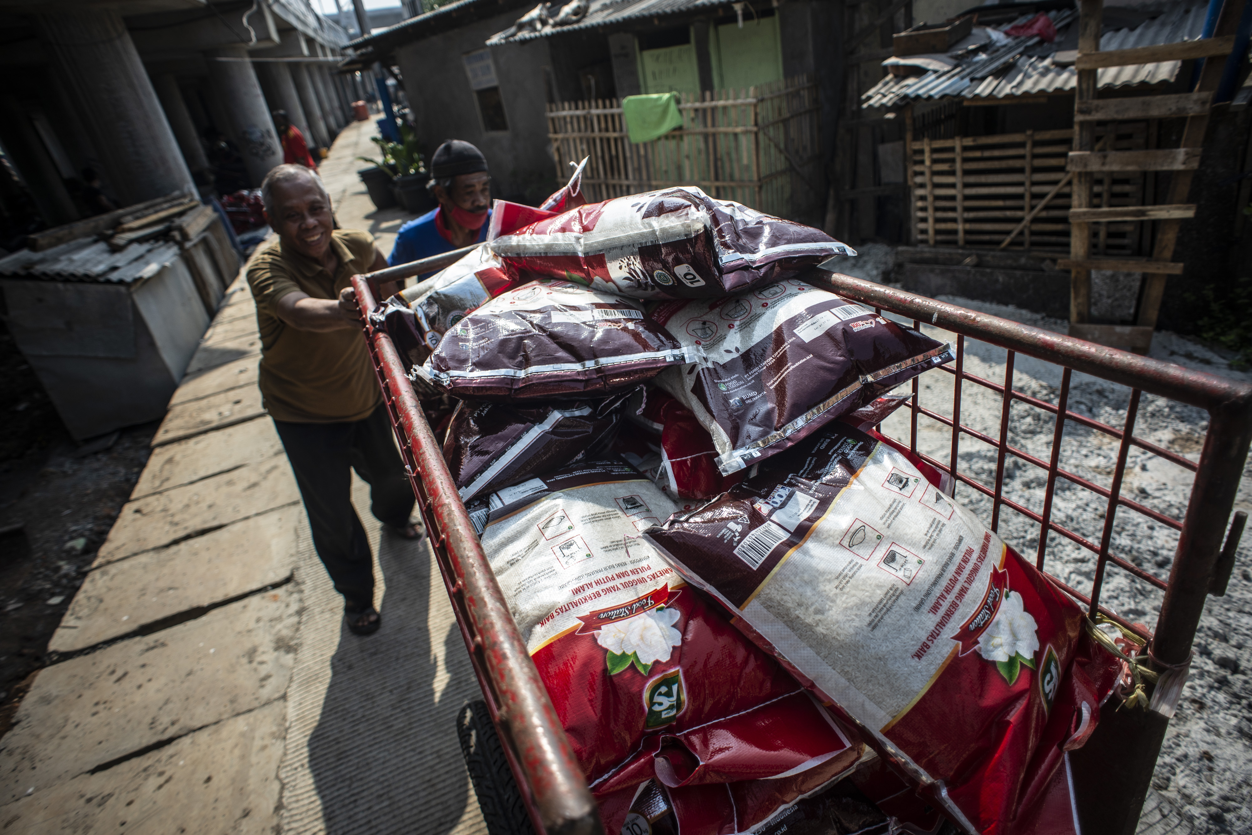 Pengurus RT mengangkut bansos non tunai berupa beras untuk disalurkan kepada warga di kawasan RW 02 Kelurahan Cakung Barat, Jakarta.