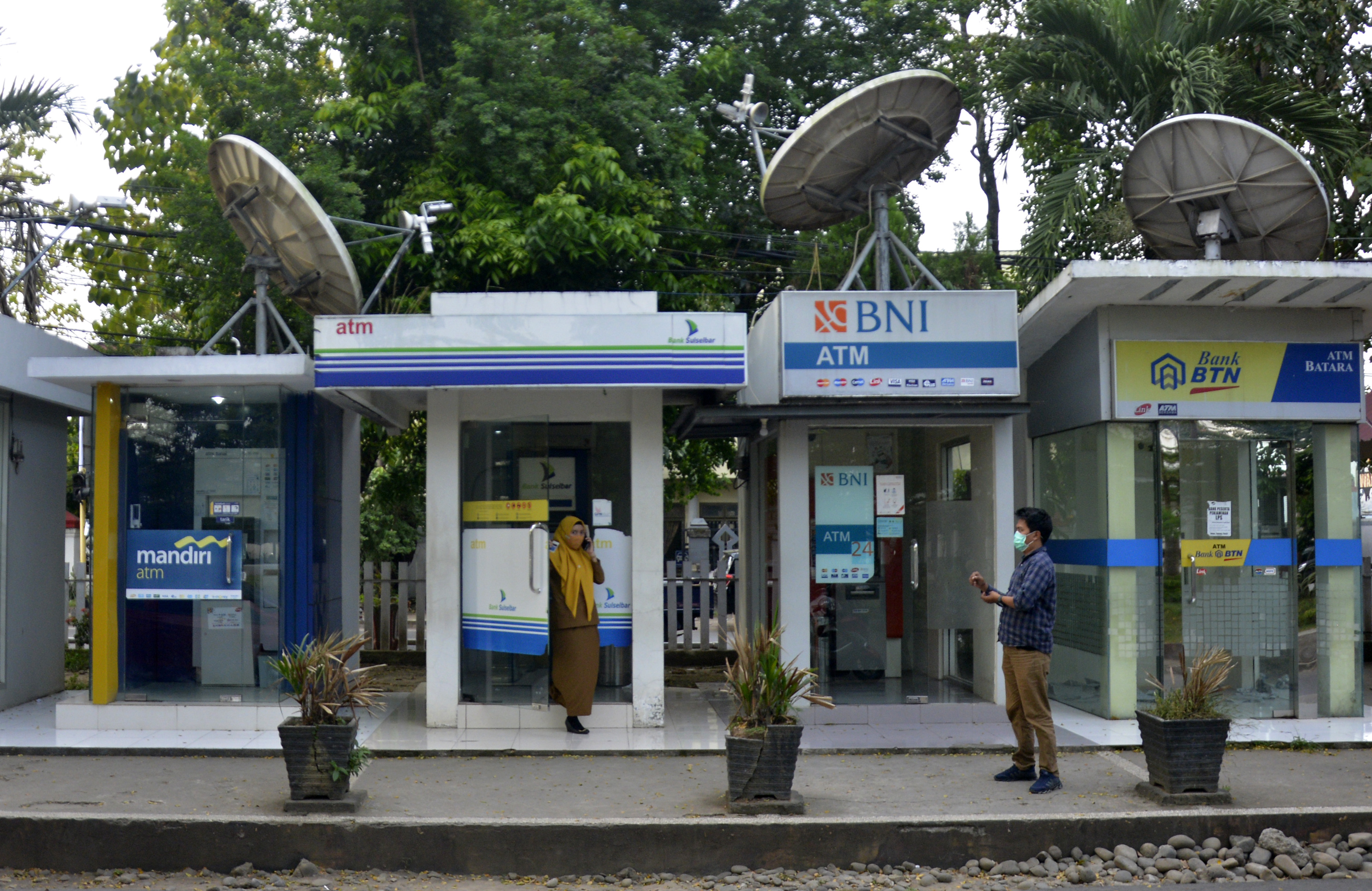 Warga keluar dari ATM bank Himbara usai di halaman kantor Bupati Kabupaten Gowa, Sulawesi Selatan, Senin (31/5).