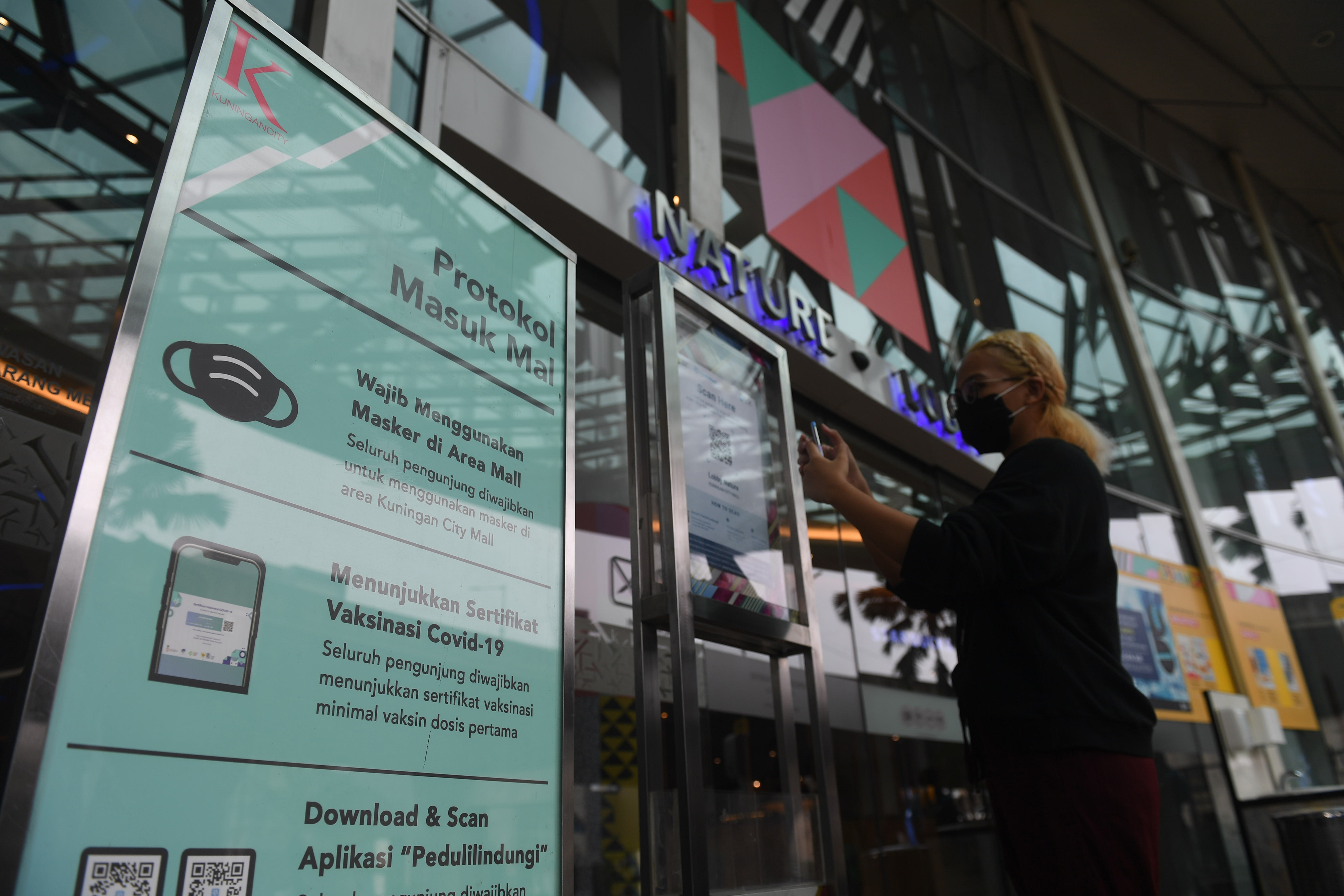 Pengunjung memindai barcode melalui aplikasi PeduliLindungi sebelum memasuki Mall Kuningan City di Jakarta.