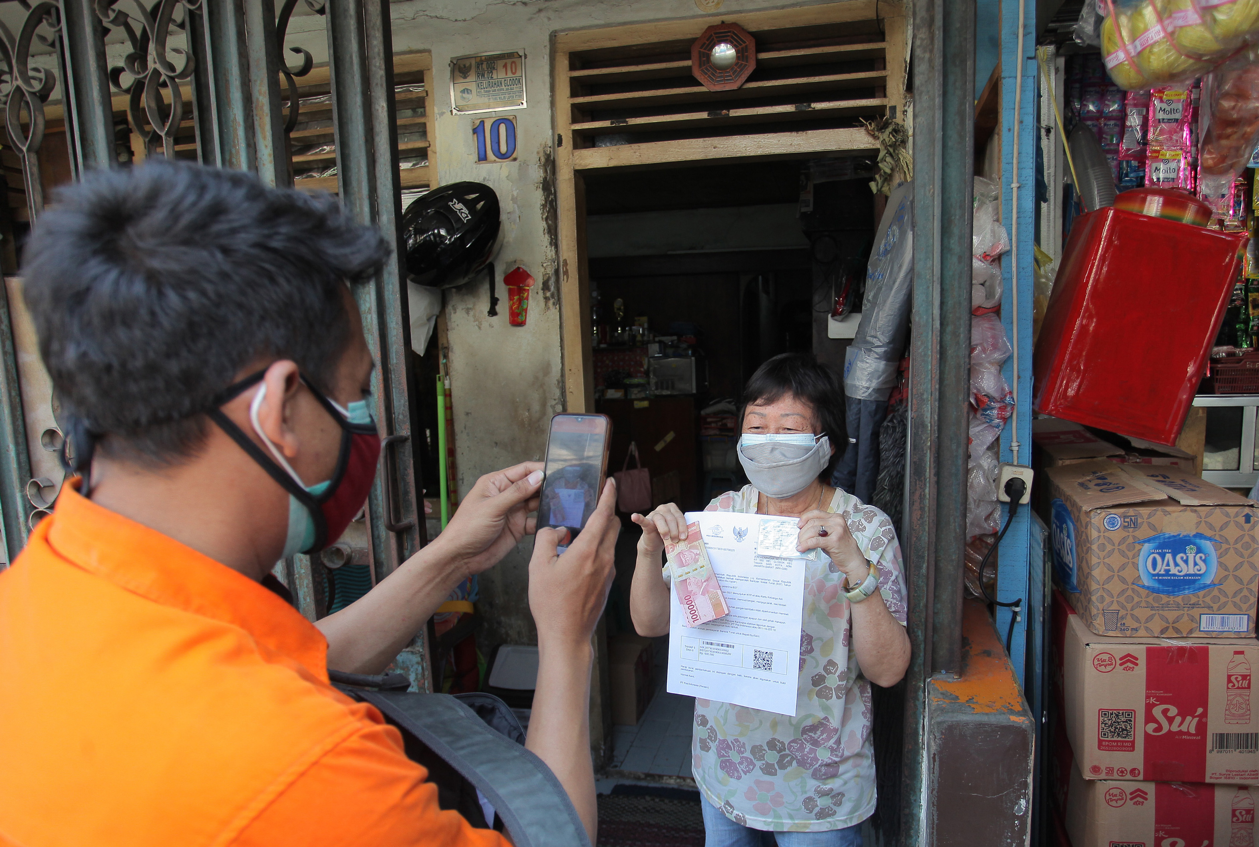 Petugas mendokumentasikan distribusi bansos tunai untuk warga di kawasan Glodok, Jakarta.