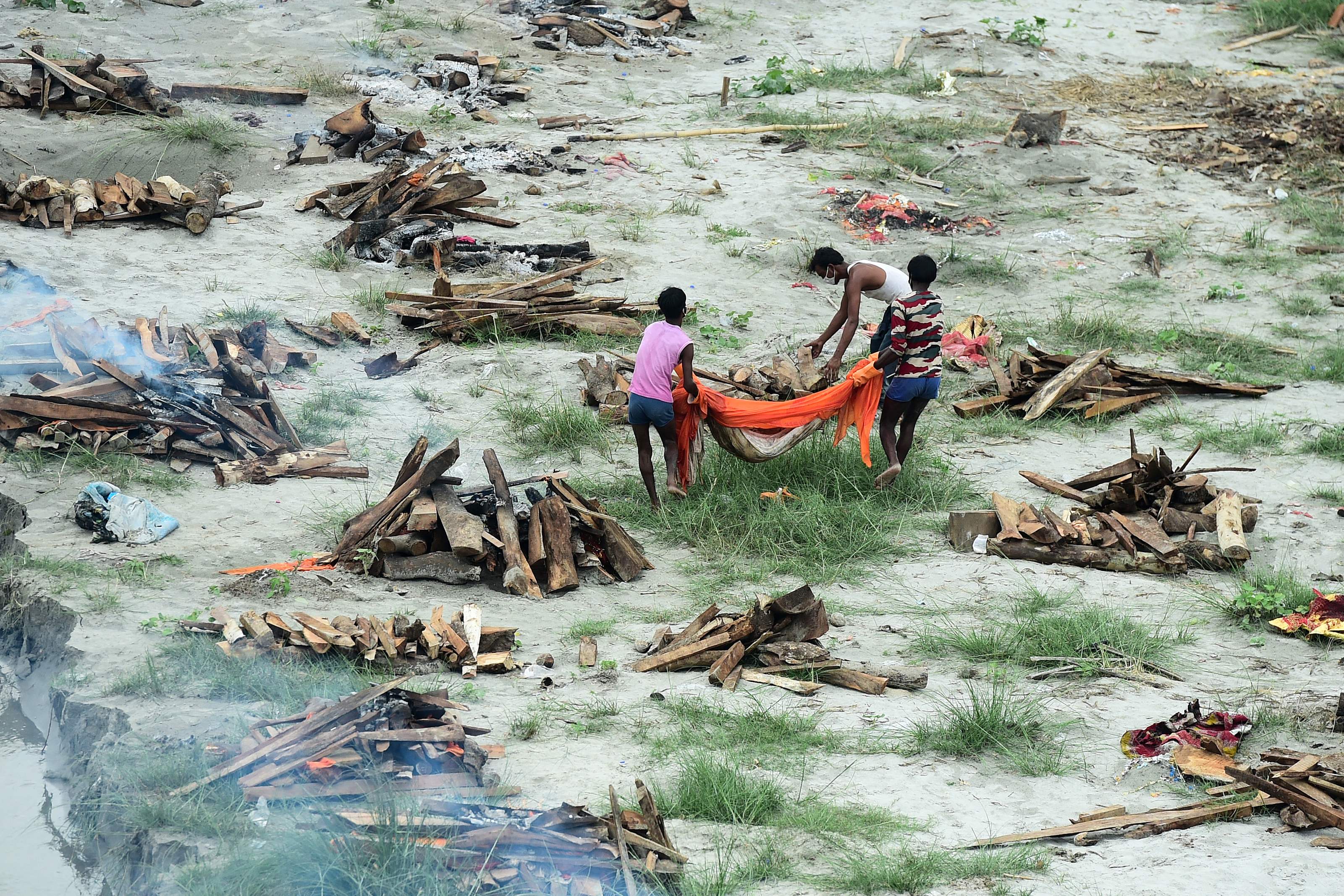 Petugas melakukan kremasi pasien Covid-19 yang meninggal di tepian Sungai Gangga, Negara Bagian Allahabad, India.   
