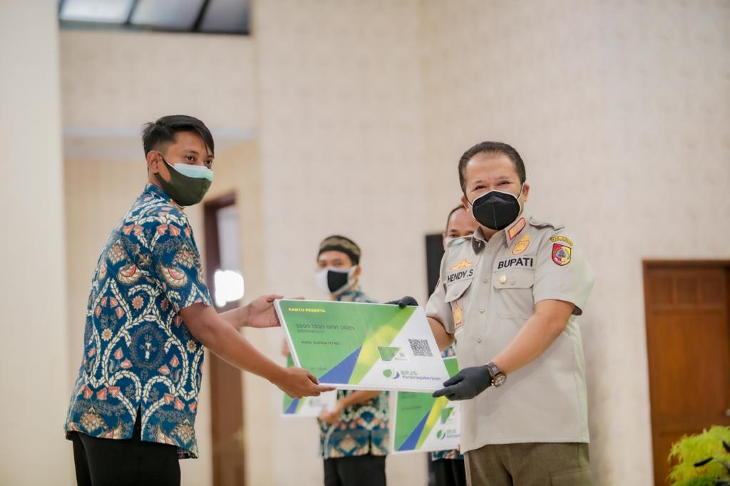  Bupati Jember Hendy Siswanto menyerahkan secara simbolis  kartu kepesertaan BPJAMSOSTEK kepada perwakilan Ketua RT RW, Sabtu (7/8/2021).