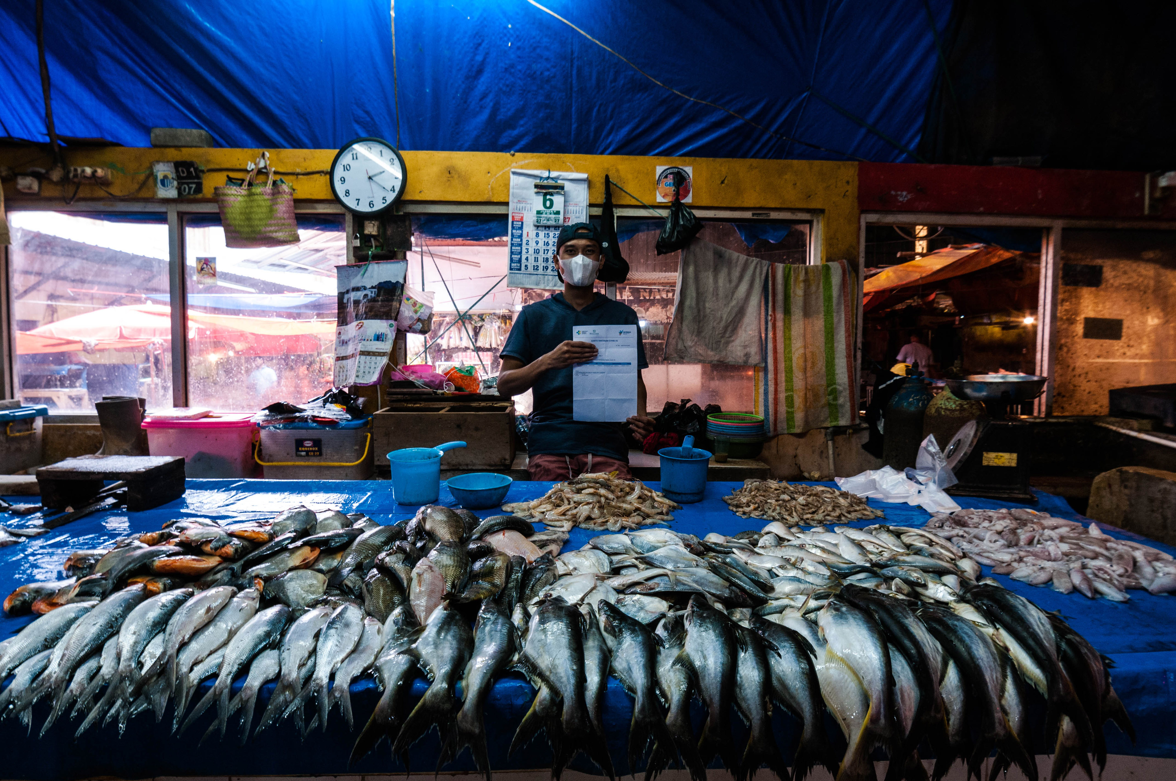 Pedagang di pasar tradisional rangkasbitung, Lebak, Banten menunjukkan kartu vaksinasi Covid-19