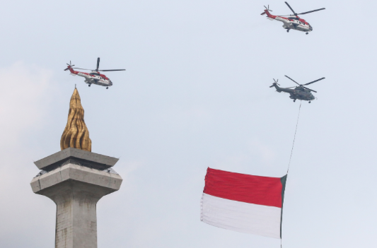 Tiga helikopter TNI AU terbang melintas sambil mengibarkan bendera merah putih saat Upacara Peringatan Detik-Detik Proklamasi.